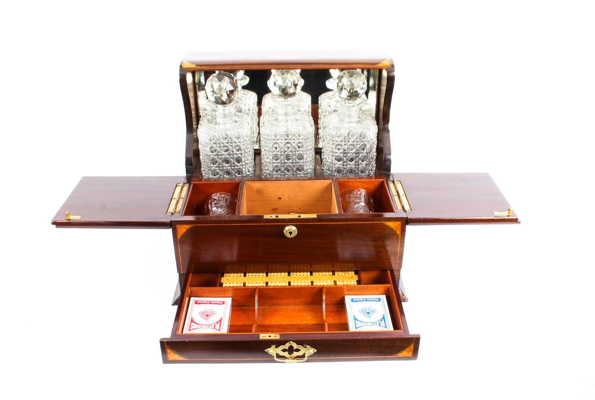 This is a superb antique Victorian mahogany cased three decanter Tantalus with decorative inlaid decoration, circa 1870 in date.

It was skillfully crafted in mahogany with beautiful shell and line inlaid decoration, stylish silver plated handles