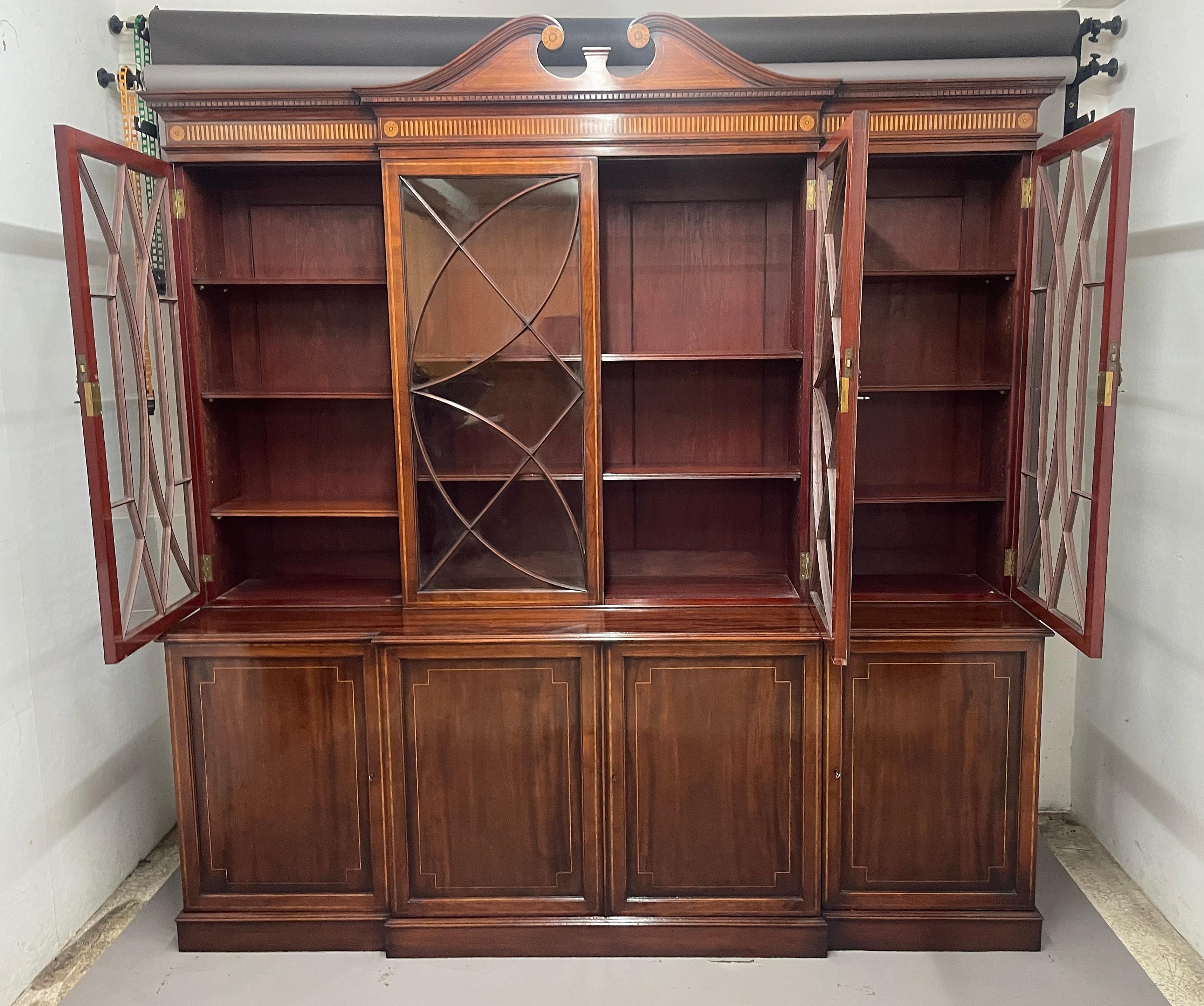 Una favolosa libreria a due ante in mogano intarsiato del XIX secolo, con un cornicione modanato con modanatura a dentelli e un frontone a collo di cigno al centro con intarsi decorativi a ventaglio circolari, il fregio sottostante con ulteriori
