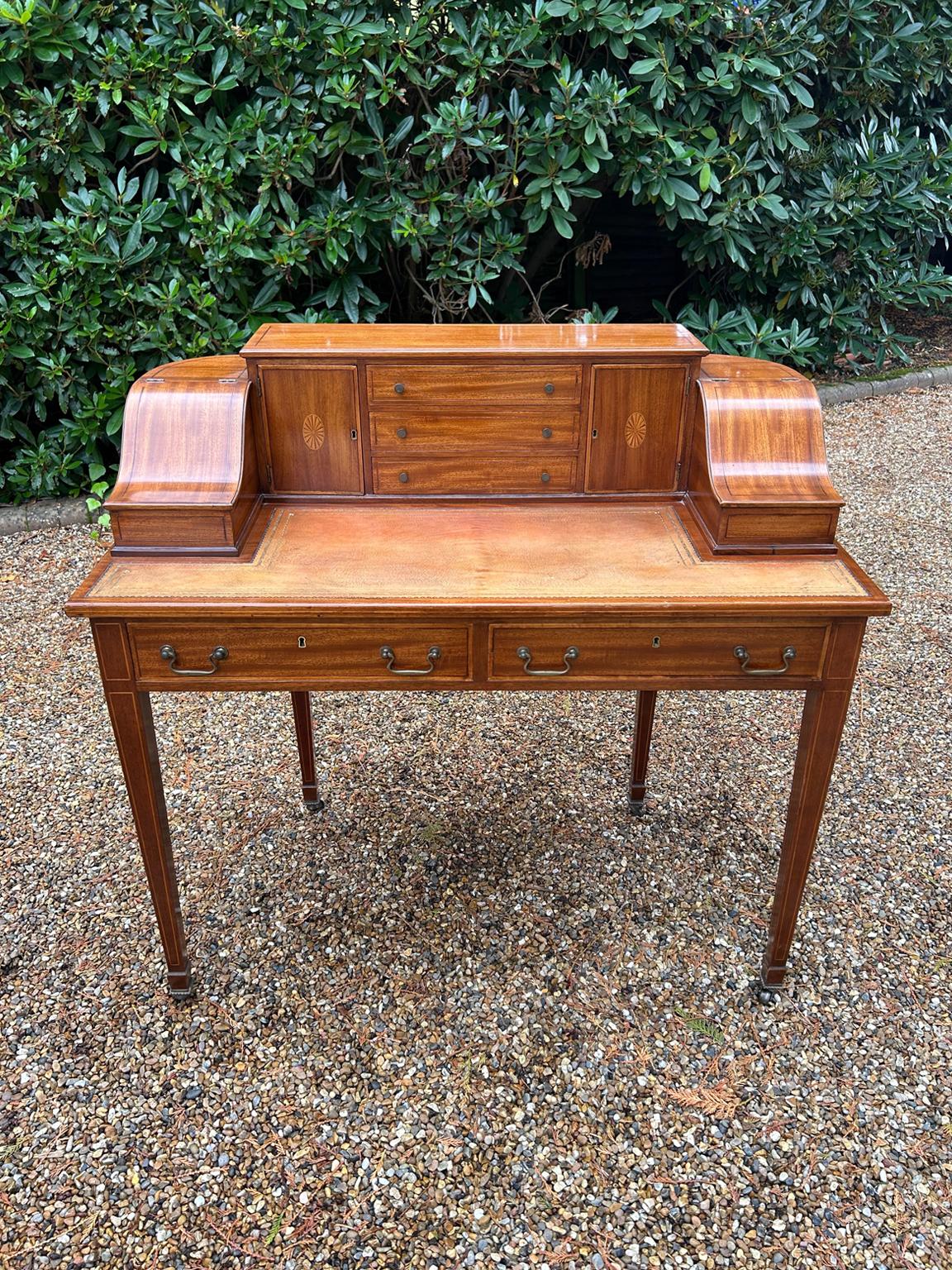 A high quality 19th Century Inlaid Mahogany Carlton House Desk. The top has three middle drawers inbetween two cupboard and two lift up compartments. Below the writing surface there are two mahogany lined drawers with brass handles. The whole desk