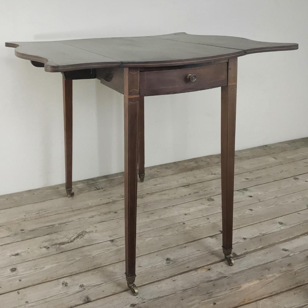 19th century inlaid mahogany drop leaf table is an excellent early example of adaptive furniture, where independent leaves on each side tuck down when not in use to save space, but pop up with swivel-out supports underneath when extra space is