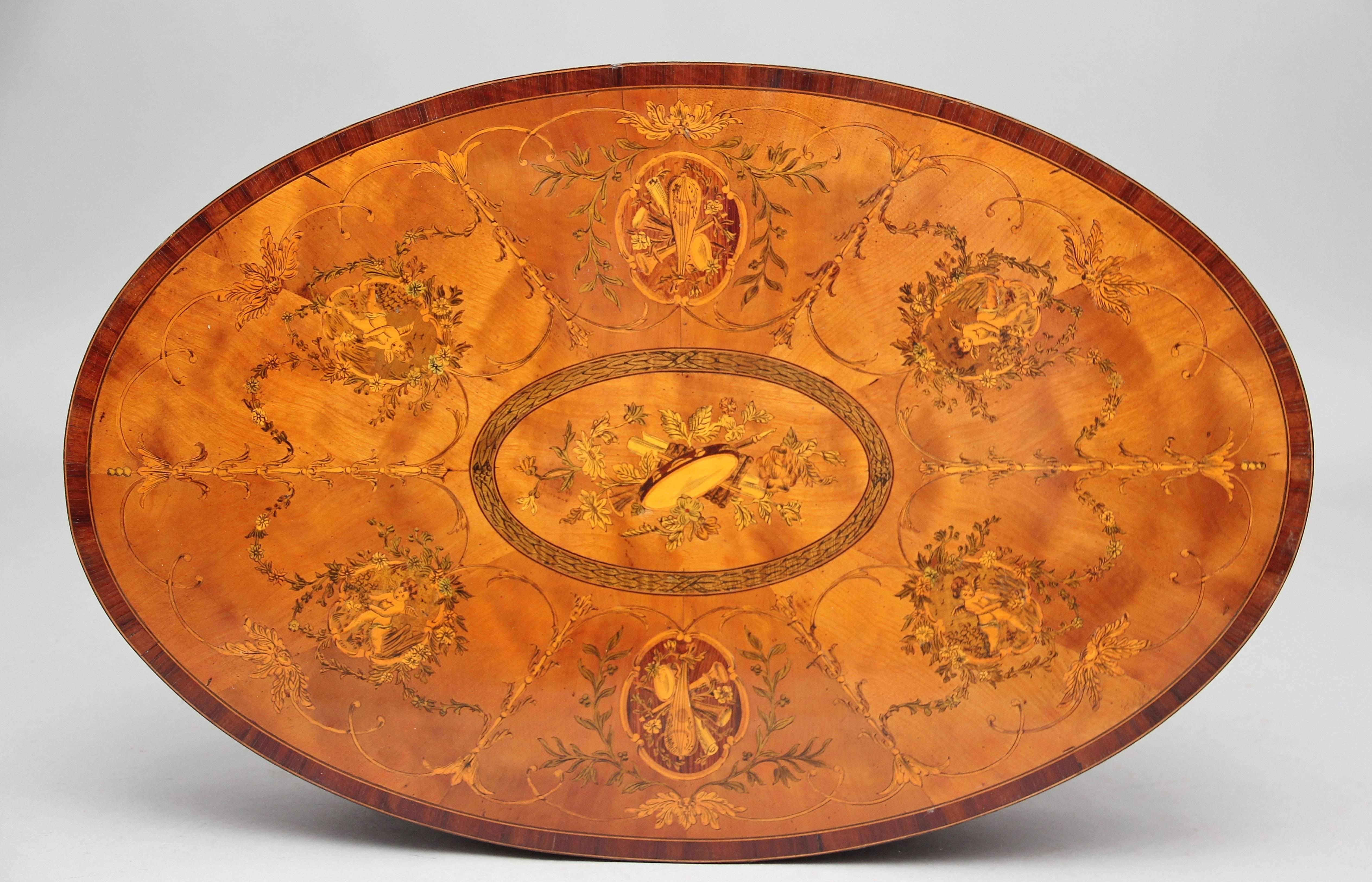 An exhibition quality 19th century inlaid satinwood centre / occasional table in the Sheraton style, profusely inlaid all-over, the oval top having walnut crossbanding, an oval panel at the centre with floral and musical decoration, the rest of the