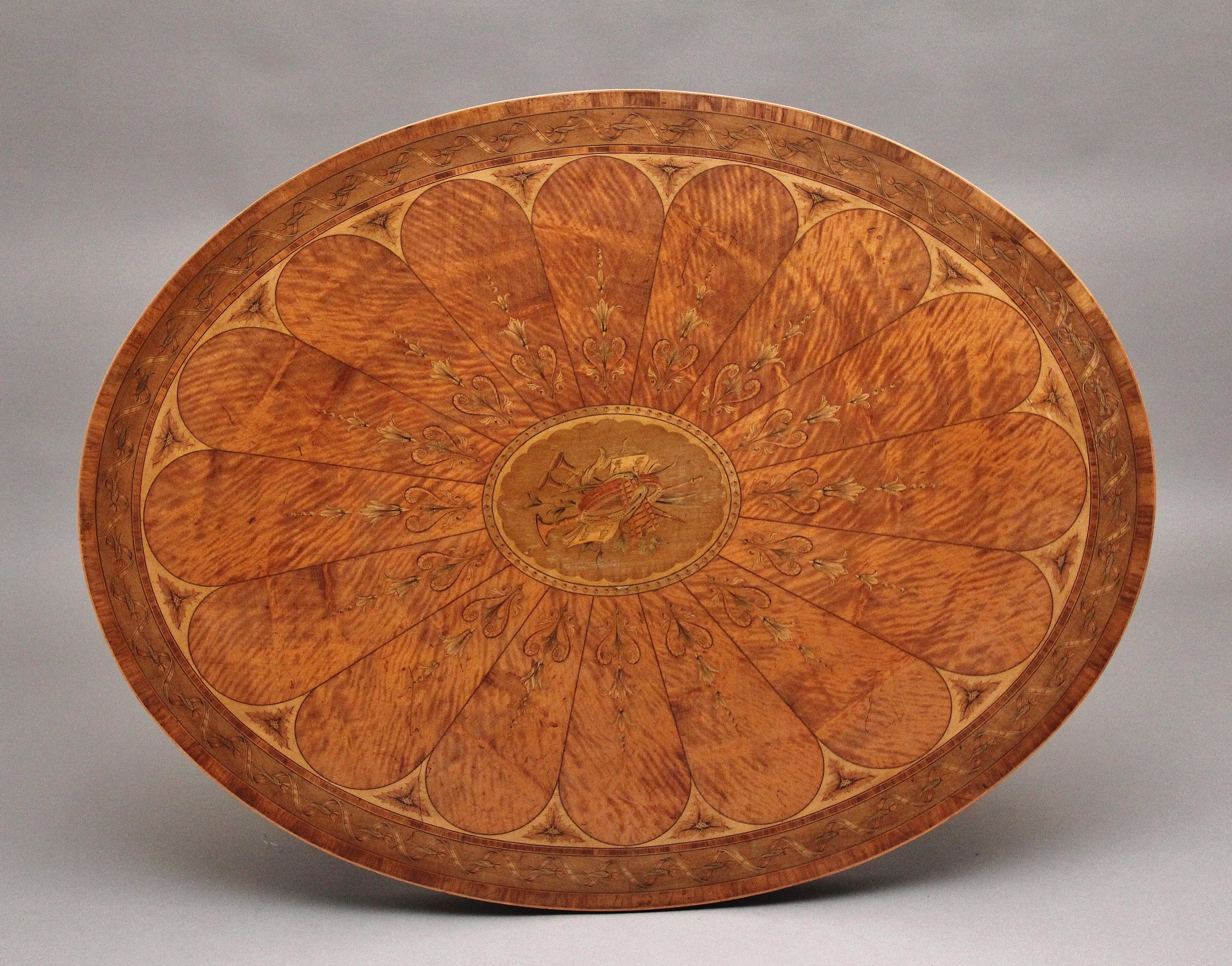 Ein hochdekorativer und qualitativ hochwertiger Tisch aus satiniertem Holz des 19. Jahrhunderts im Sheraton-Stil. Die ovale Platte ist über und über mit Intarsien aus verschiedenen Pflanzen, geformten Paneelen und einer komplizierten