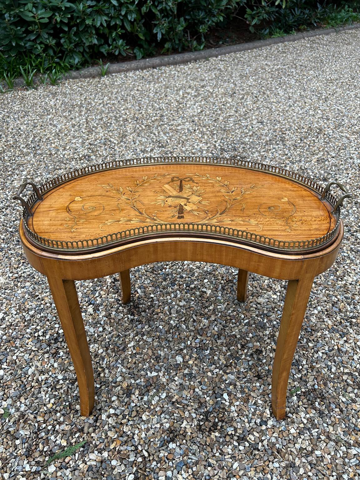 19th Century Satinwood Kidney Shaped Inlaid Tray on stand. The inlay shows ribbons, bows, scrolls, garlands of flowers. Around the edge there is a brass gallery & carrying handles. The tray stands on a removable later stand.

Circa: 1890 /