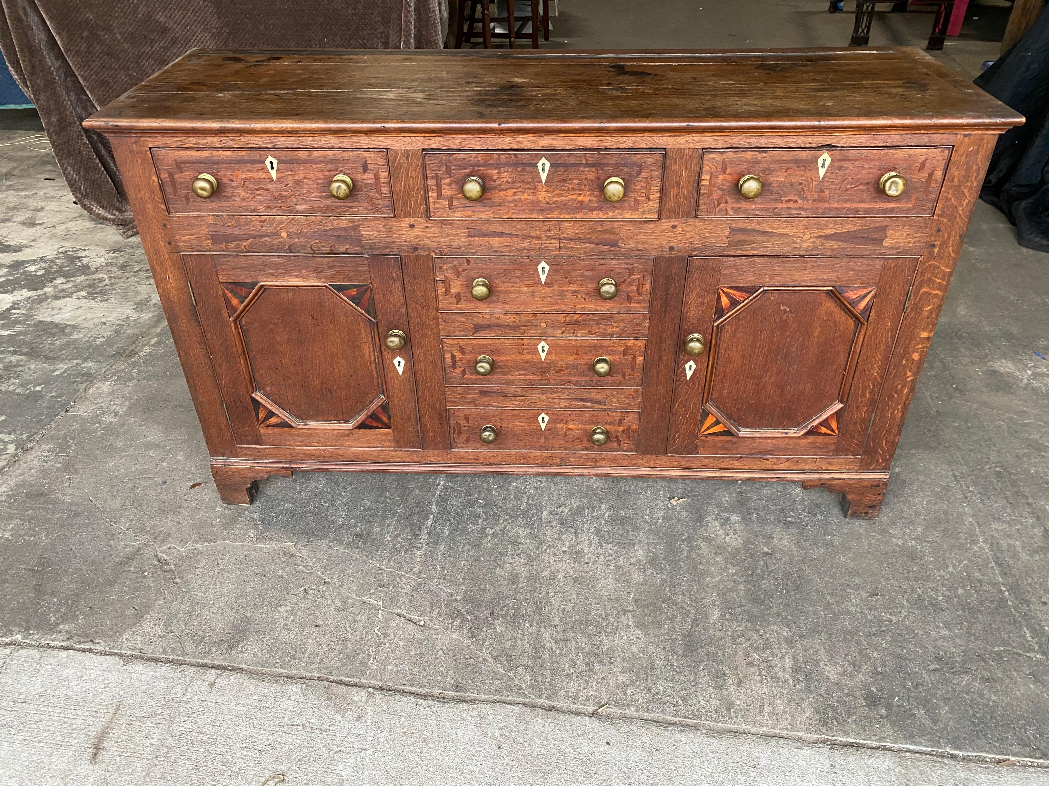 19th century inlaid Welsh oak dresser base with 3 drawers over 2 doors and 3 faux drawers. Inlaid eschuteons and doors. Very attractive patina and color.
