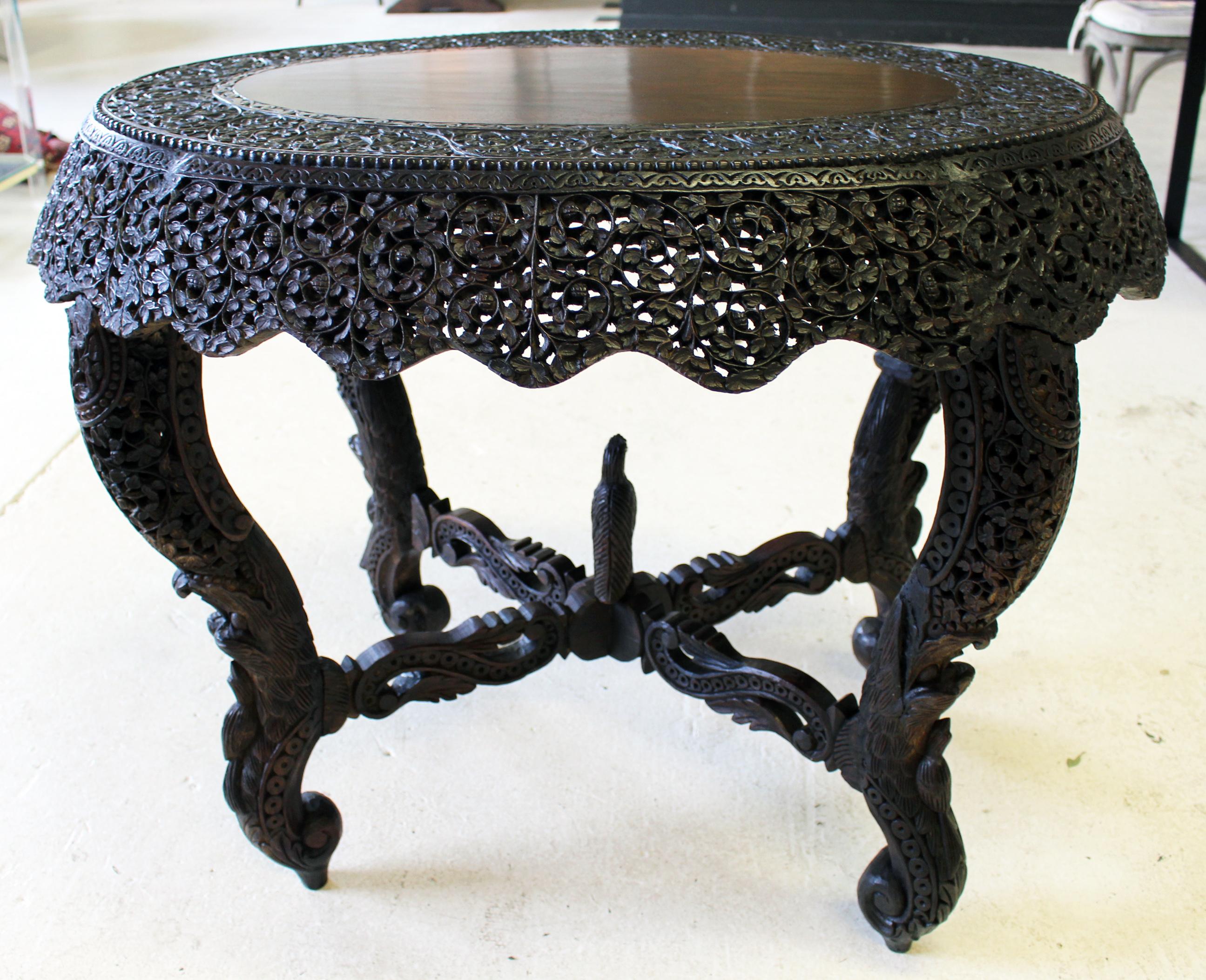 Exquisite antique Anglo-Indian center table. Exceptional, intricate and ornately hand carved wood oval table with carved frieze. Four elephant trunk design legs with carved bird nestled on bottom of each leg and carved stretchers with bird in