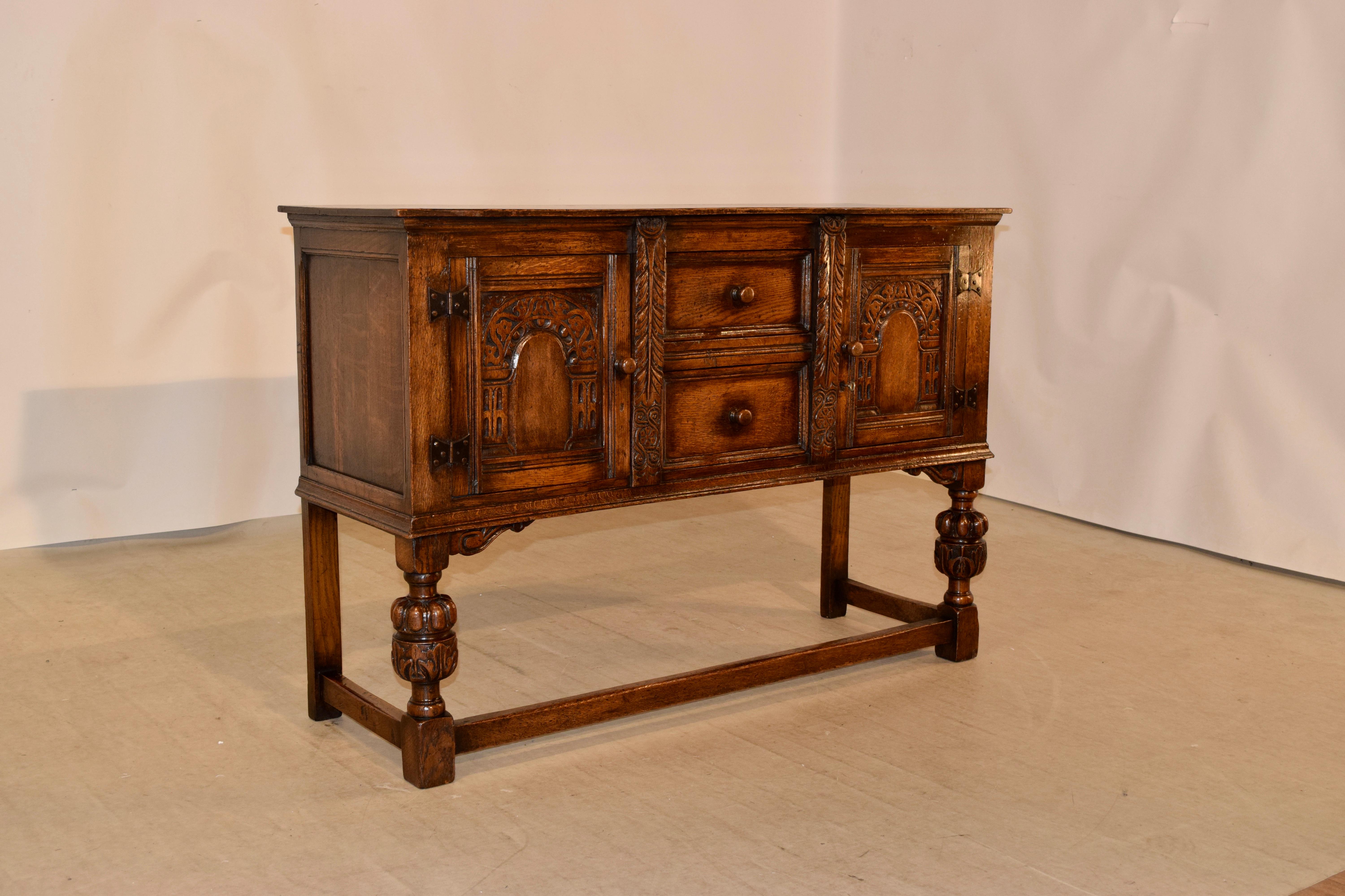Late 19th century Ipswitch oak server from England. The case contains two central drawers flanked by single doors, which open to reveal storage over hand turned and carved legs in the front and simple legs in the back for easy placement against a