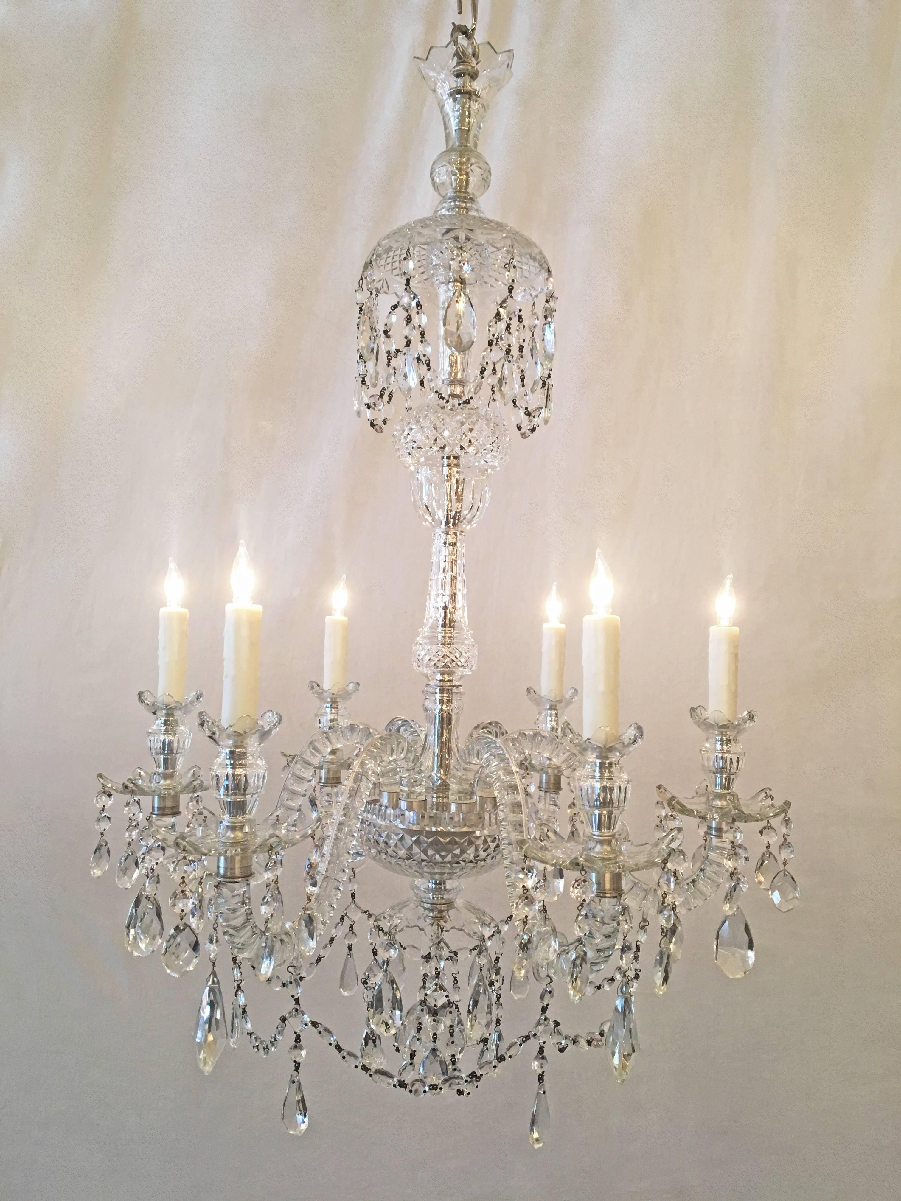 This 19th century Georgian Anglo Irish crystal chandelier that was originally candle is now French wired. The six S-scrolled arms are solid crystal with hand-cut thumbnail reeding. Contains beautiful crystal bobeches. Chandelier is silver plate