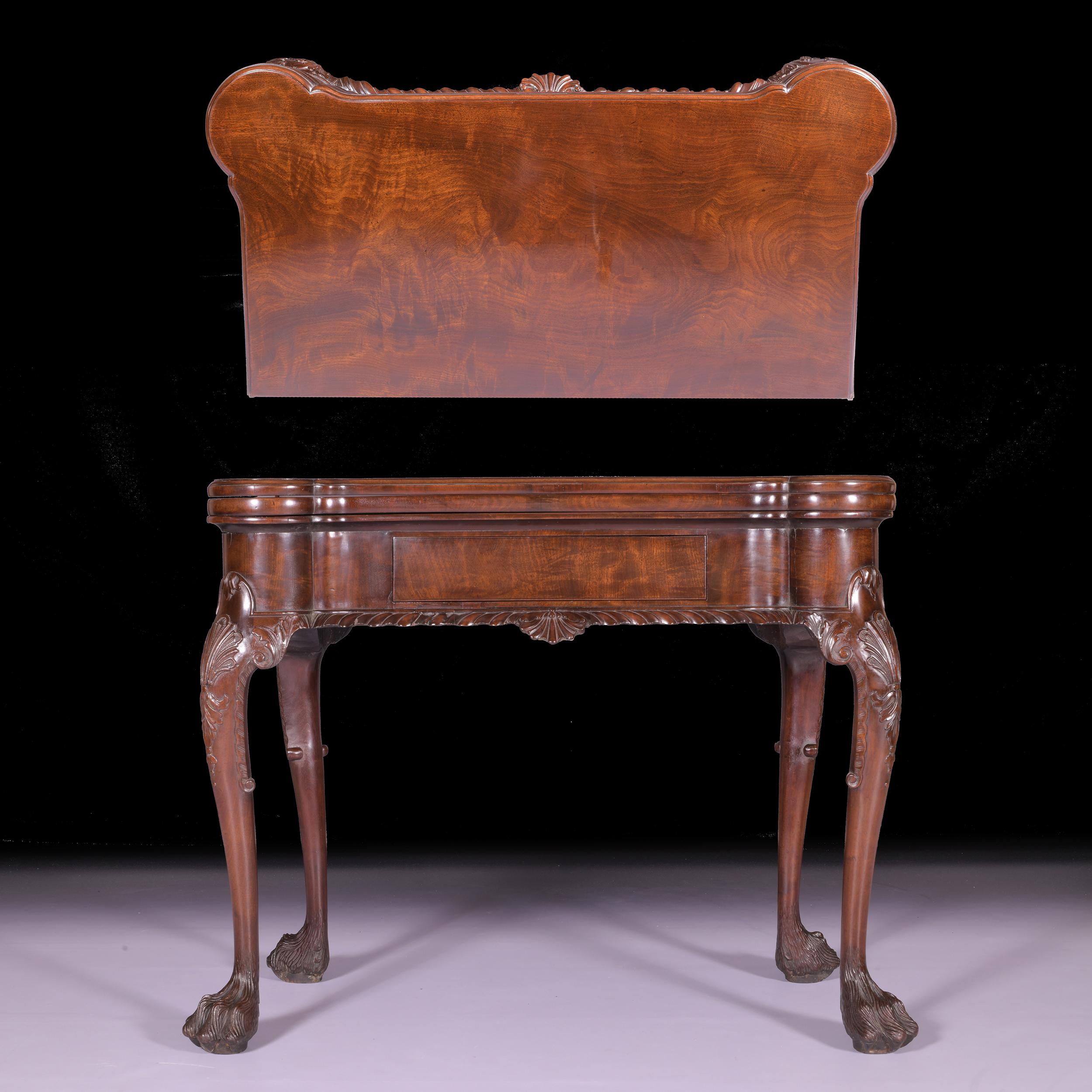 An exceptional 19th century Irish George II style mahogany games and tea table of eared rectangular form, the first hinged top on solid mahogany, the second hinged top enclosing a baize surface with playing counter wells and candle stands, above an
