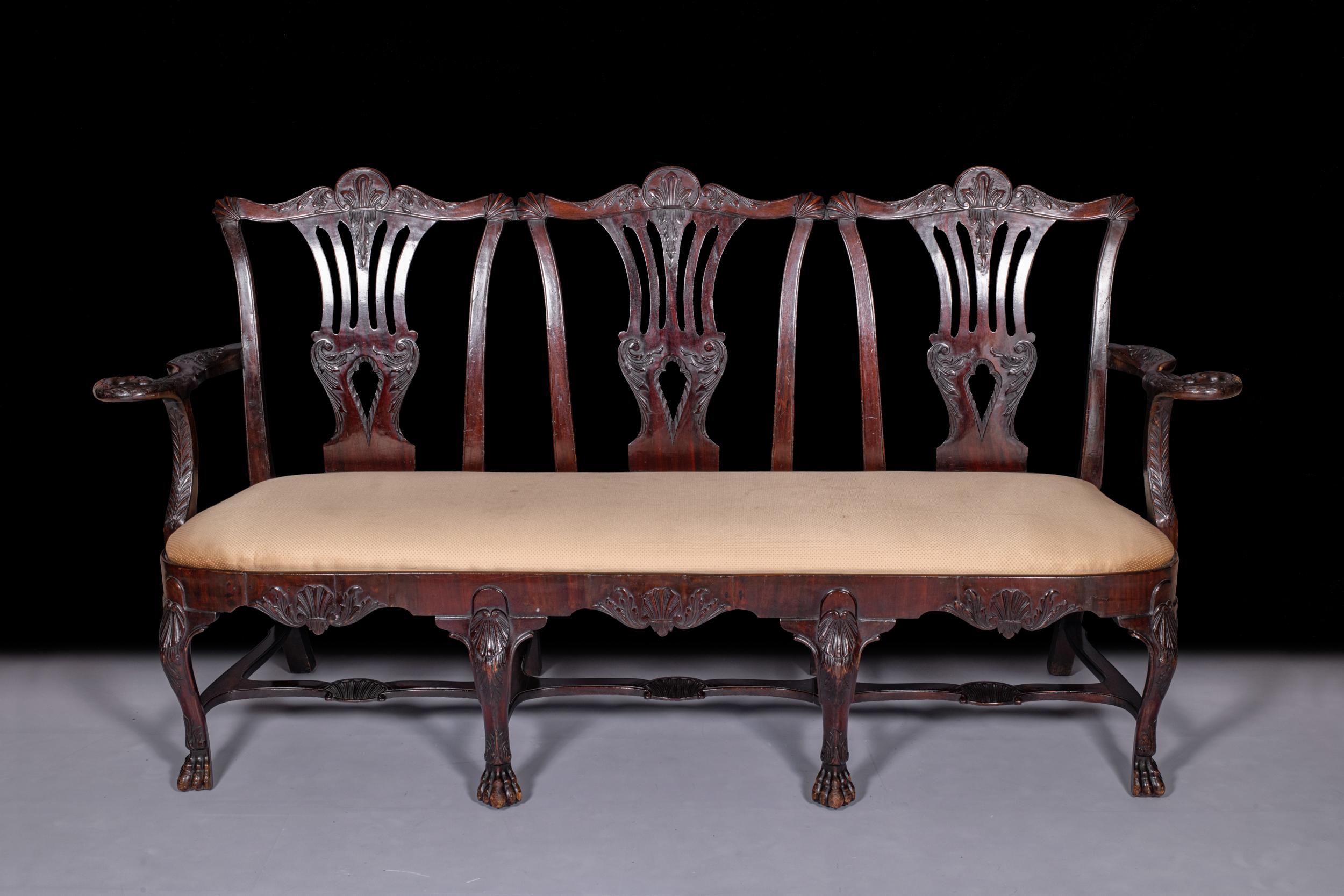 A very fine 19th century Irish carved mahogany triple chair back settee by Butler of Dublin in the 18th century style, each back crested with a shell, above a leaf carved, pierced scroll splat, above a drop in seat, flanked with shaped arm rests,
