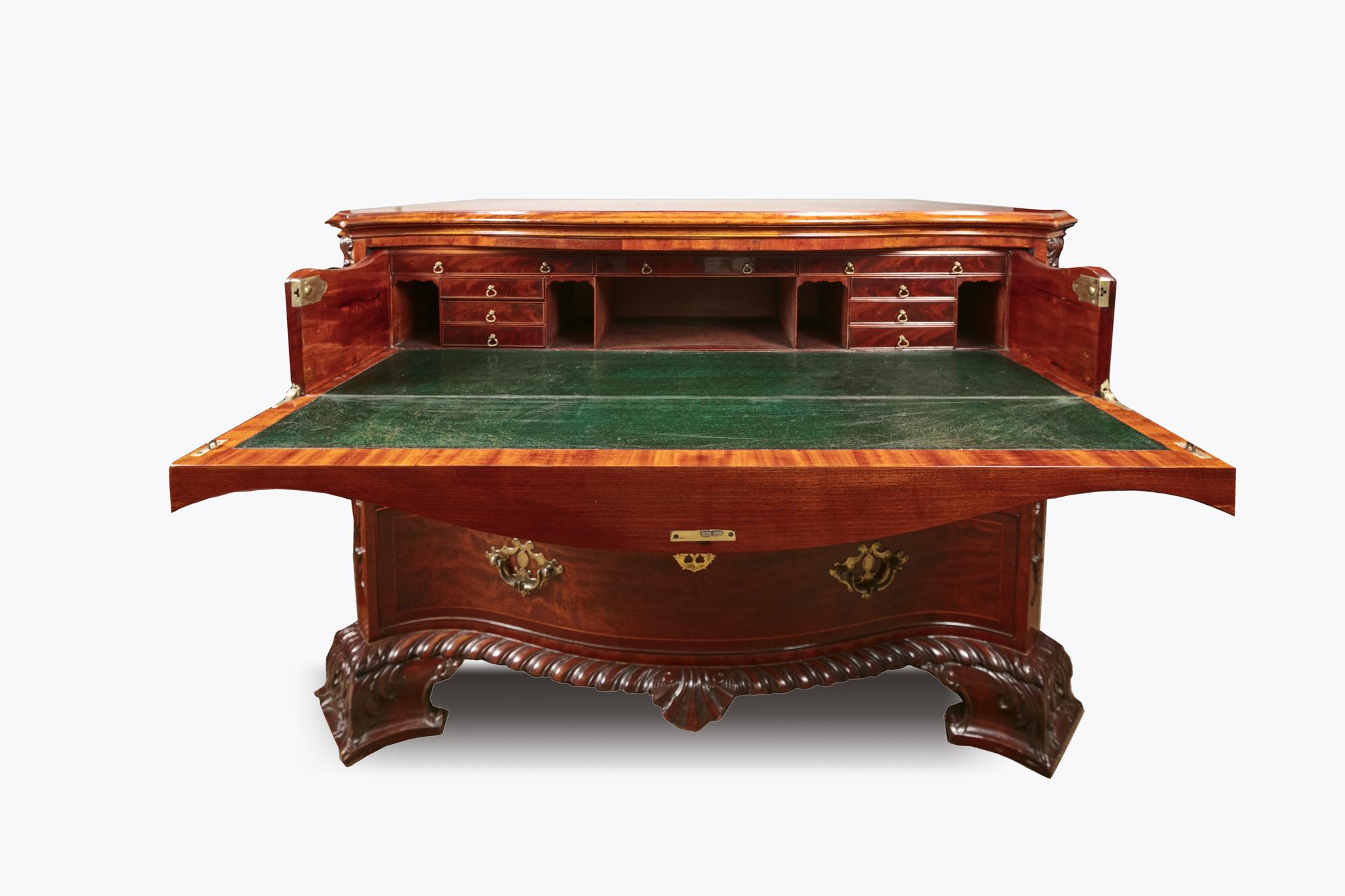 Commodo secretaire in mogano irlandese del XIX secolo. Il fronte è a serpentina, con la parte anteriore che cade per rivelare il piano di scrittura in pelle verde, e l'interno è completamente dotato di scomparti. Caratterizzato da angoli inclinati