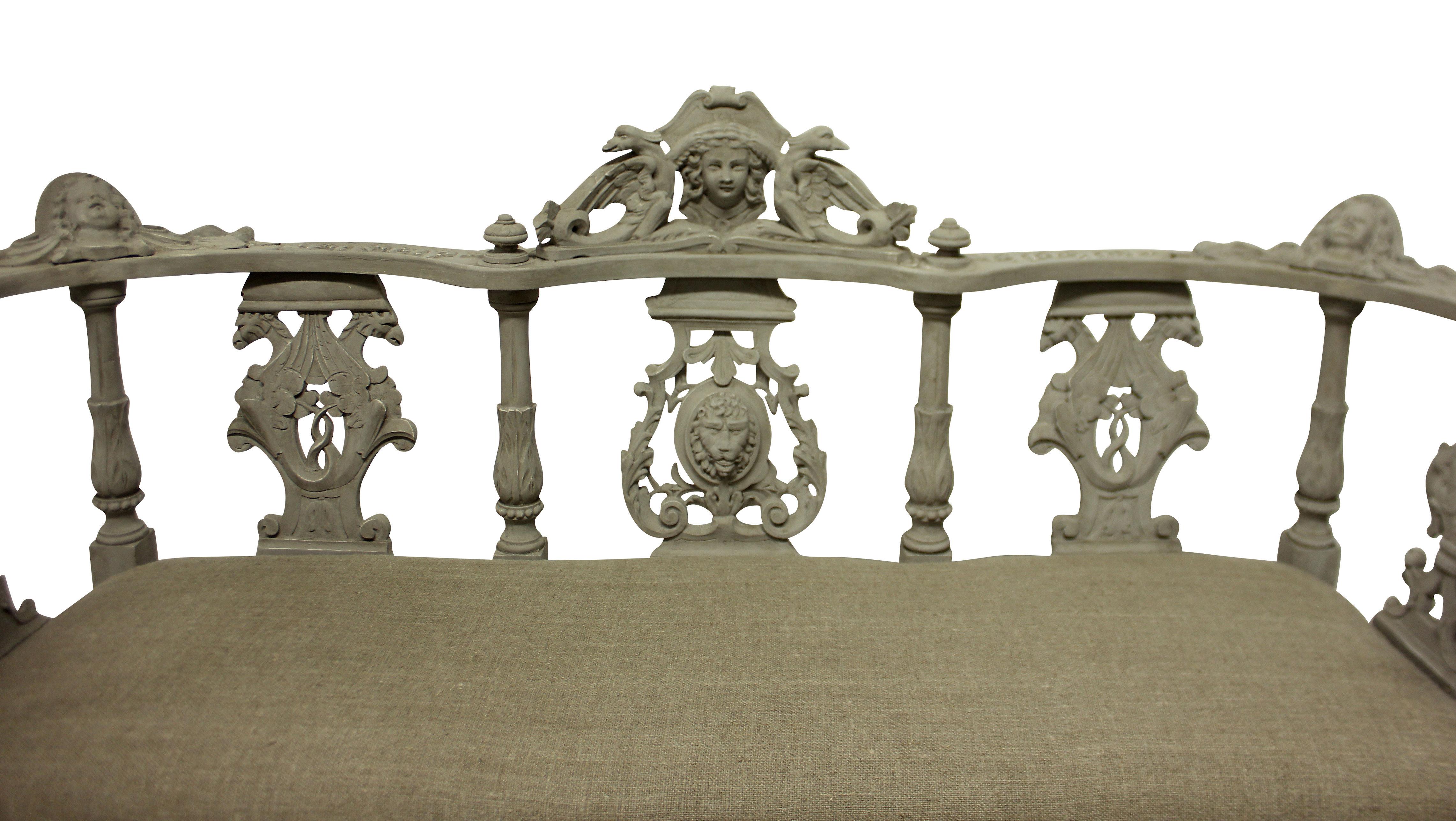 An Irish hall seat in finely carved and painted mahogany. Depicting mythological beasts, neoclassical elements and shamrock. Newly upholstered in raw linen.