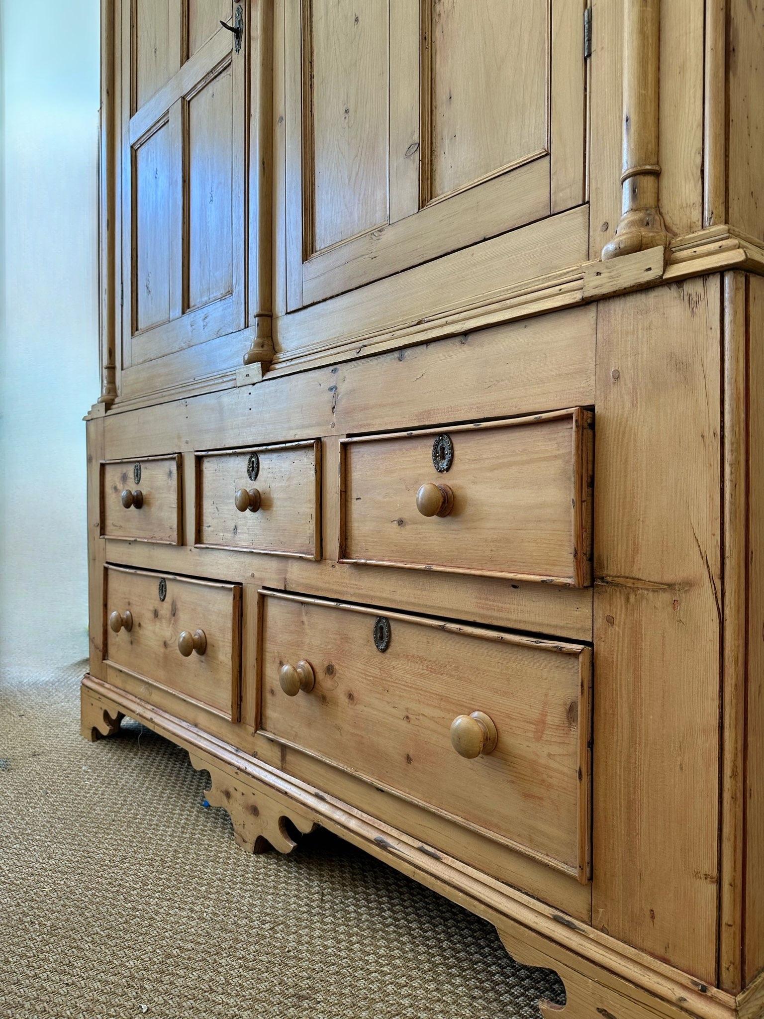 19th Century Irish Linen Press. Made of Pine with wonderful Architectural Details. Carved and moulded Cornice with three Columns Separating two Paneled Doors over base with Five original Drawers above the original decorative Bracket Feet. Great