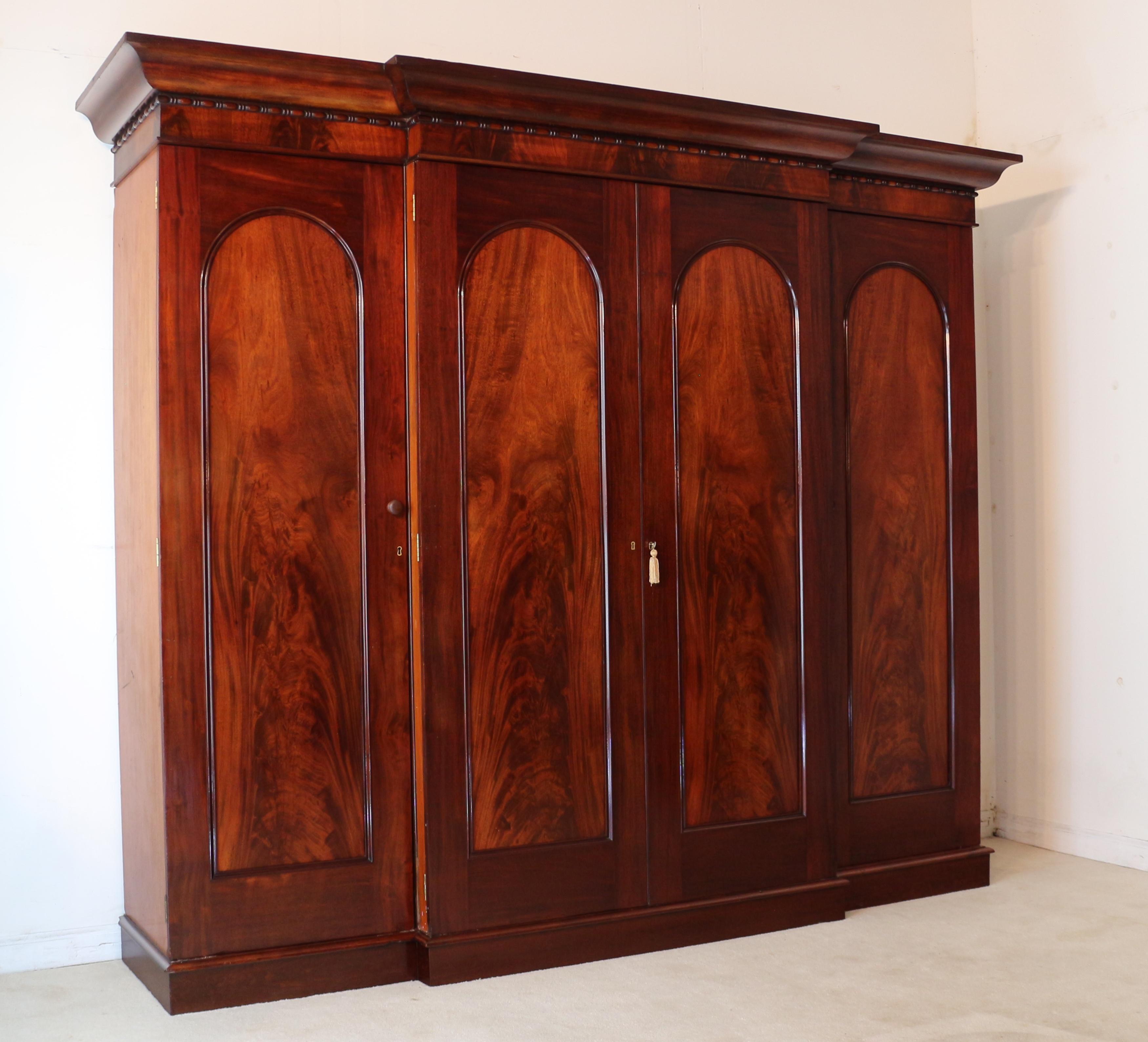A superb quality and impressive Irish early Victorian flame mahogany breakfront gentleman’s wardrobe by Robert Strahan & Co of Dublin. Made with exceptional quality timbers it has an ogee shaped cornice and bead & reel moulded frieze highlighted by