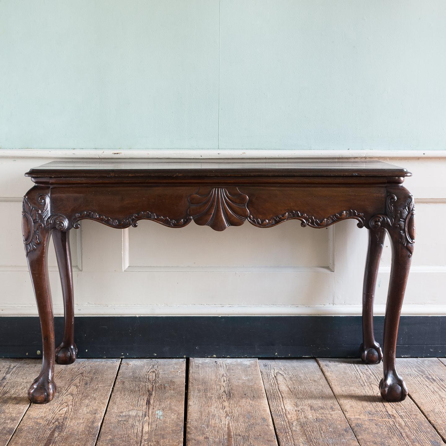 A 19th century Irish mahogany serving table in the George II style, with double moulded rectangular top above serpentine shaped frieze with S and C-scroll carved frame centred by shell detail, the cabriole legs with carved leaf and foliate designs