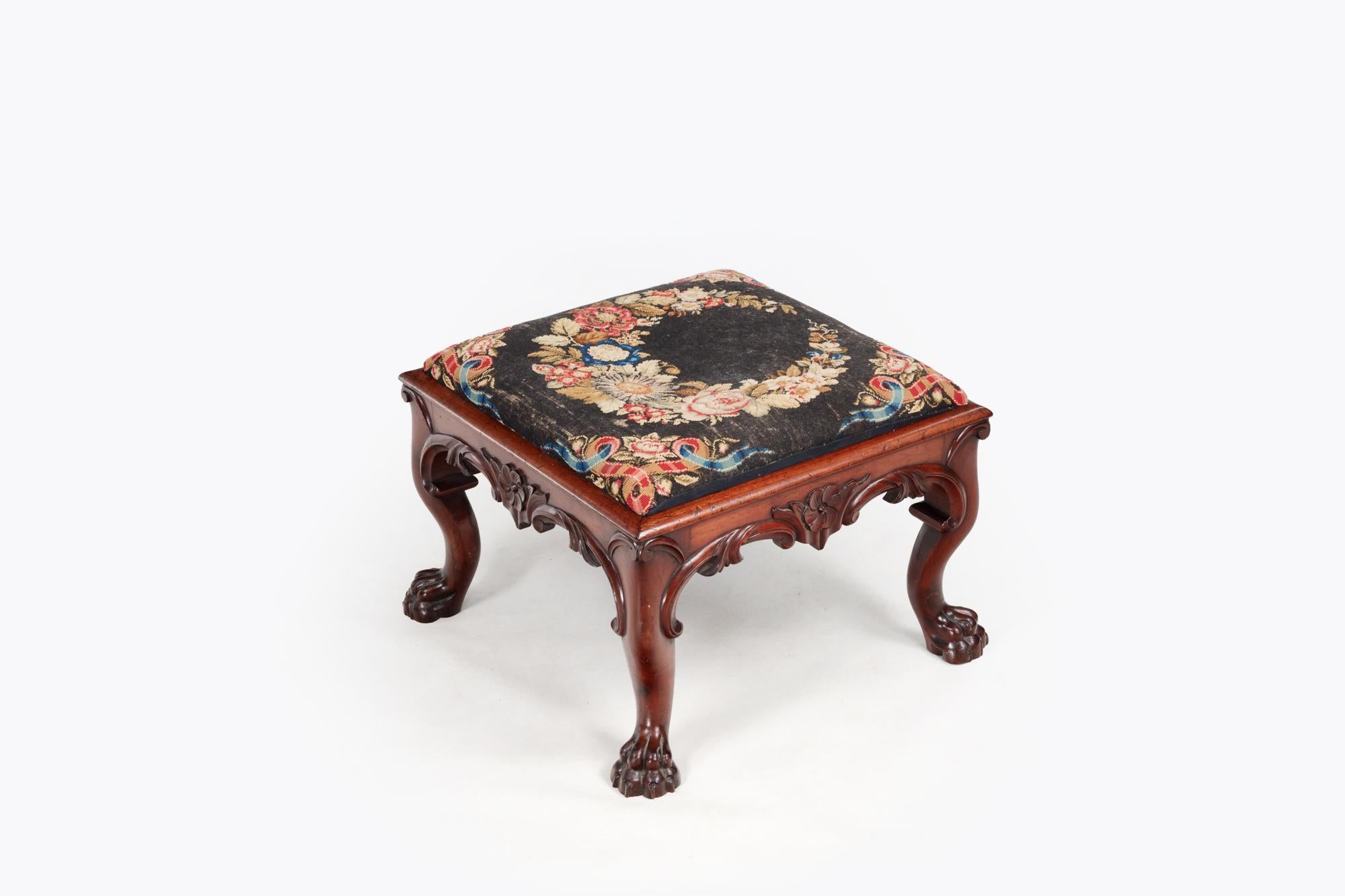 19th Century Irish mahogany square footstool with tapestry top terminating on hairy paw feet. The weight and detail of the wood carving strongly indicates that it is likely a piece produced after Robert Strahan. Circa 1830.