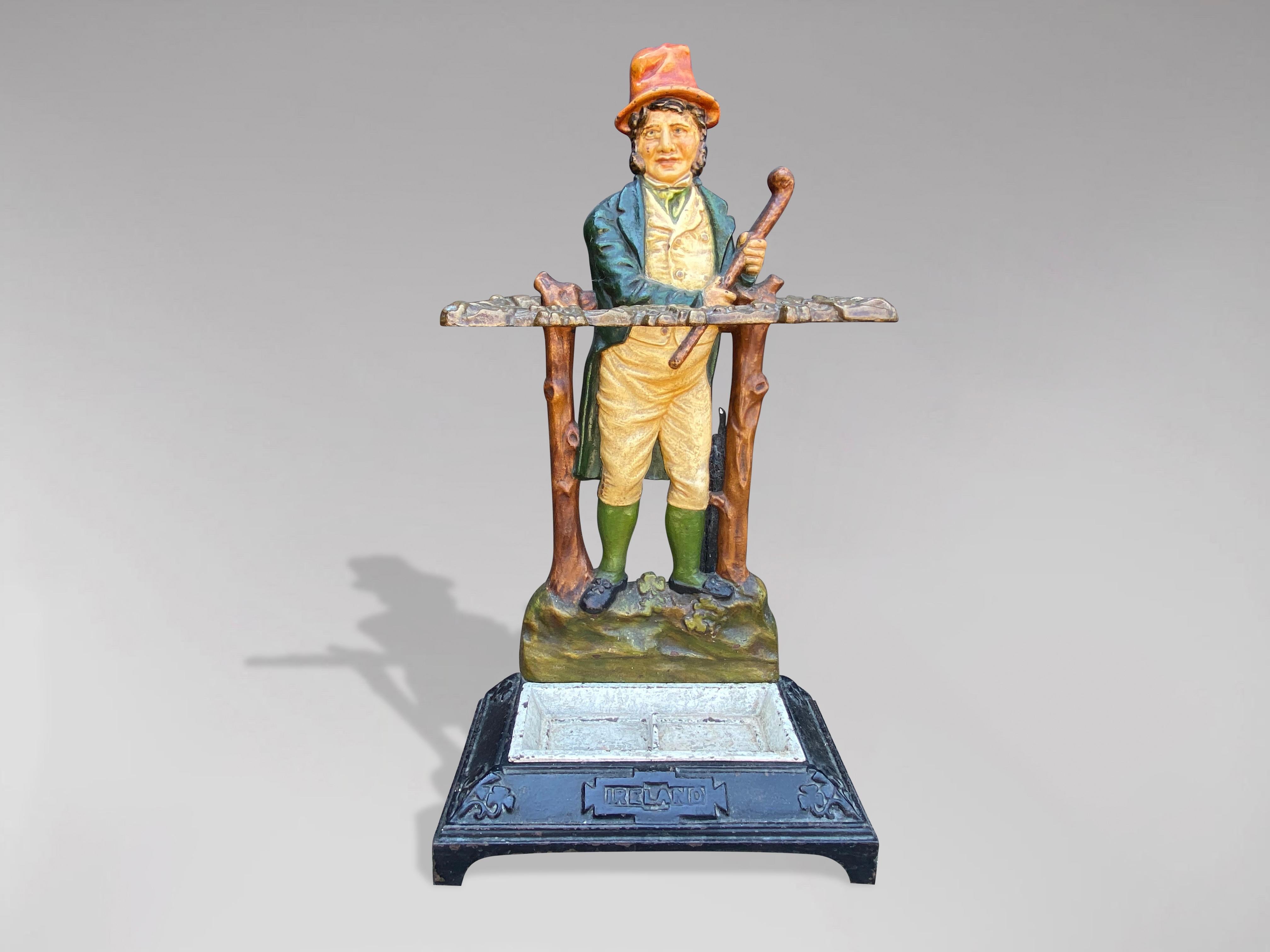 A very decorative 19th century painted cast iron stick stand or umbrella stand featuring a typical Irish folk figure holding his shillelagh. The bottom of the stand has a lift out drip tray with casting marks to the underside. With registration