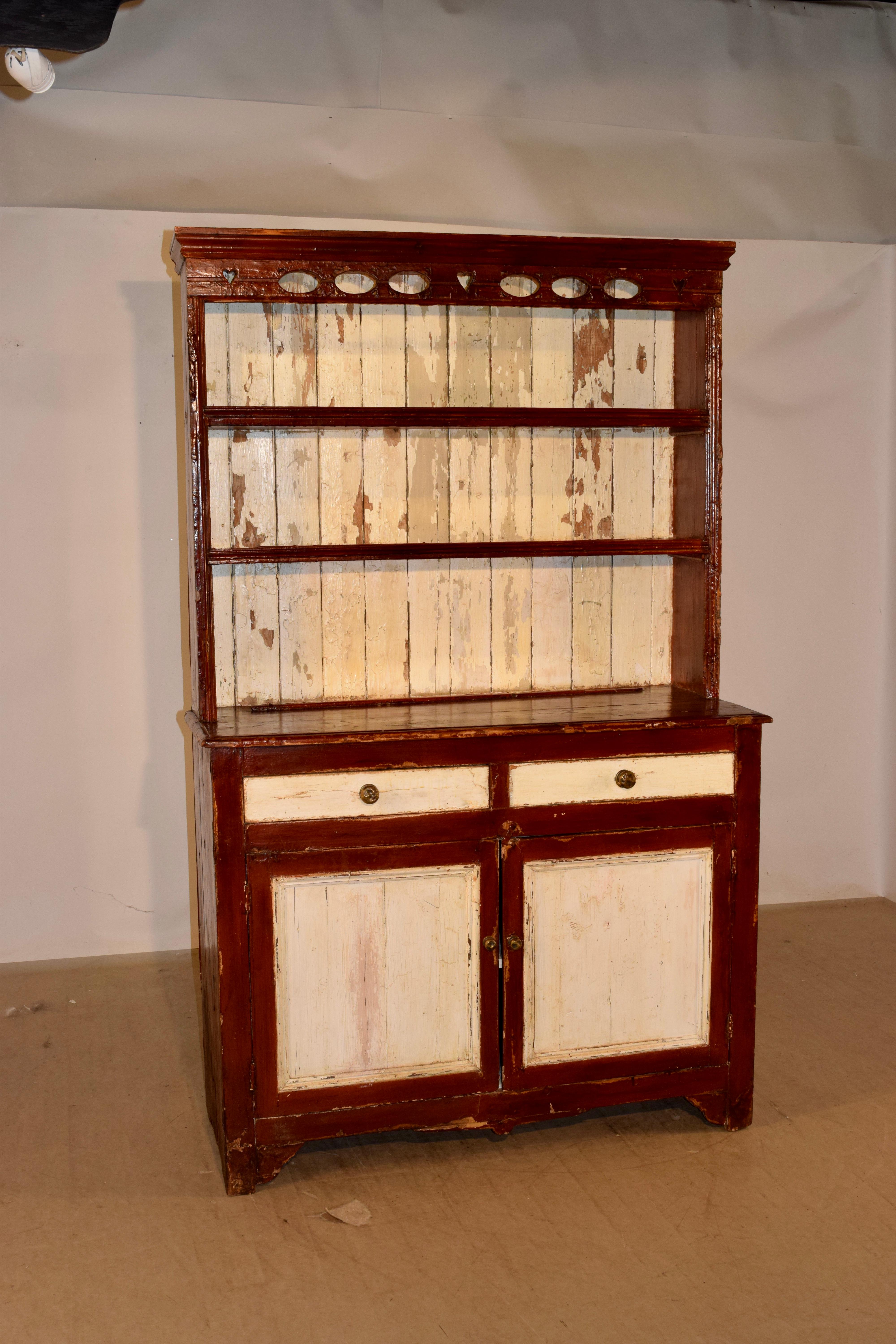 A charming Irish country painted pine step-back cupboard with three open shelves above a lower cabinet with two drawers over two doors, which open to reveal shelving. The cabinet has open fretwork at the top, beneath the crown for added interest and