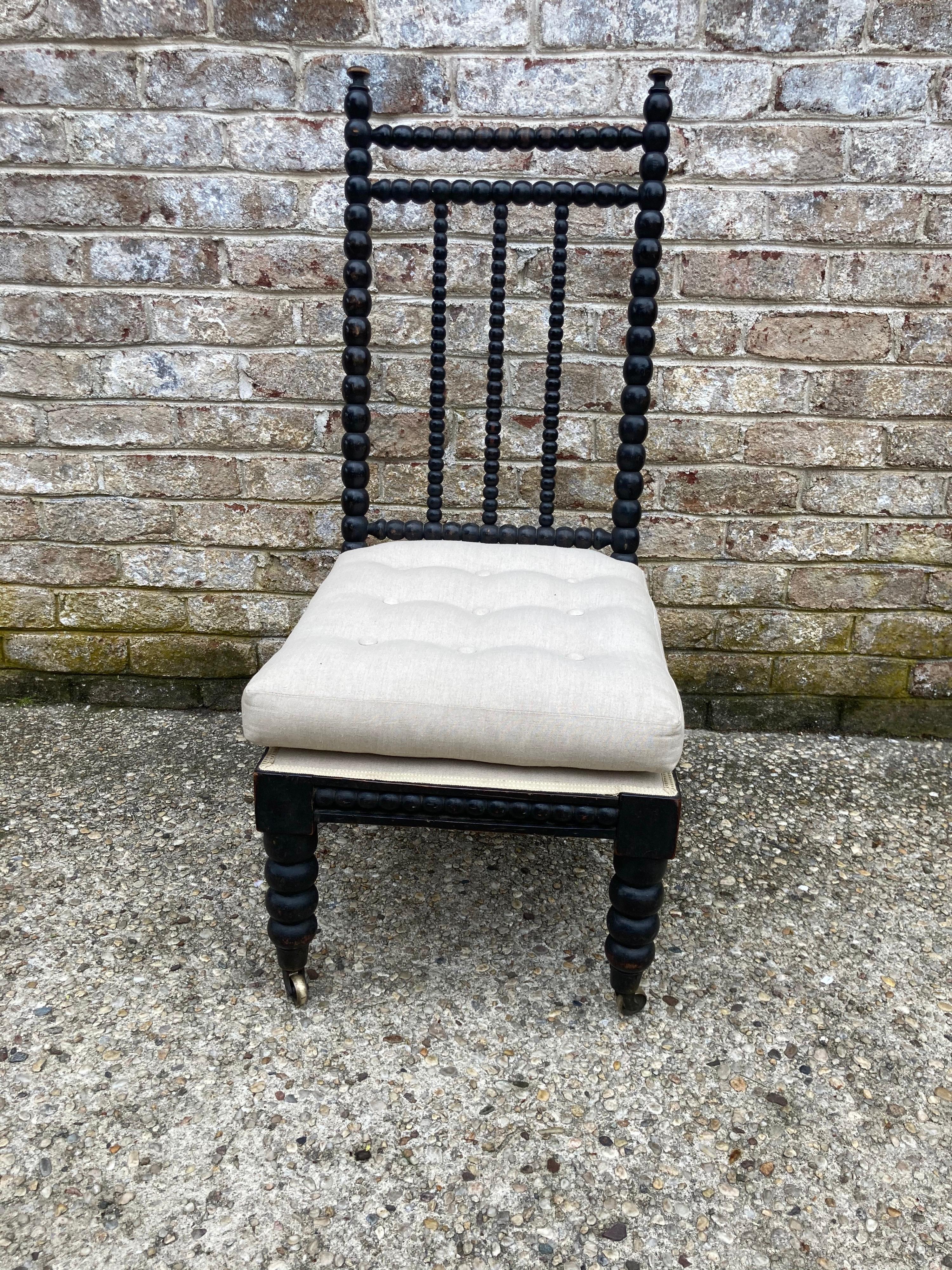Irish Spool or bobbin or turned wood chair circa 19th c.... black worn finish.... upholstered in a off white linen with a tufted pillow seat and matching decking....