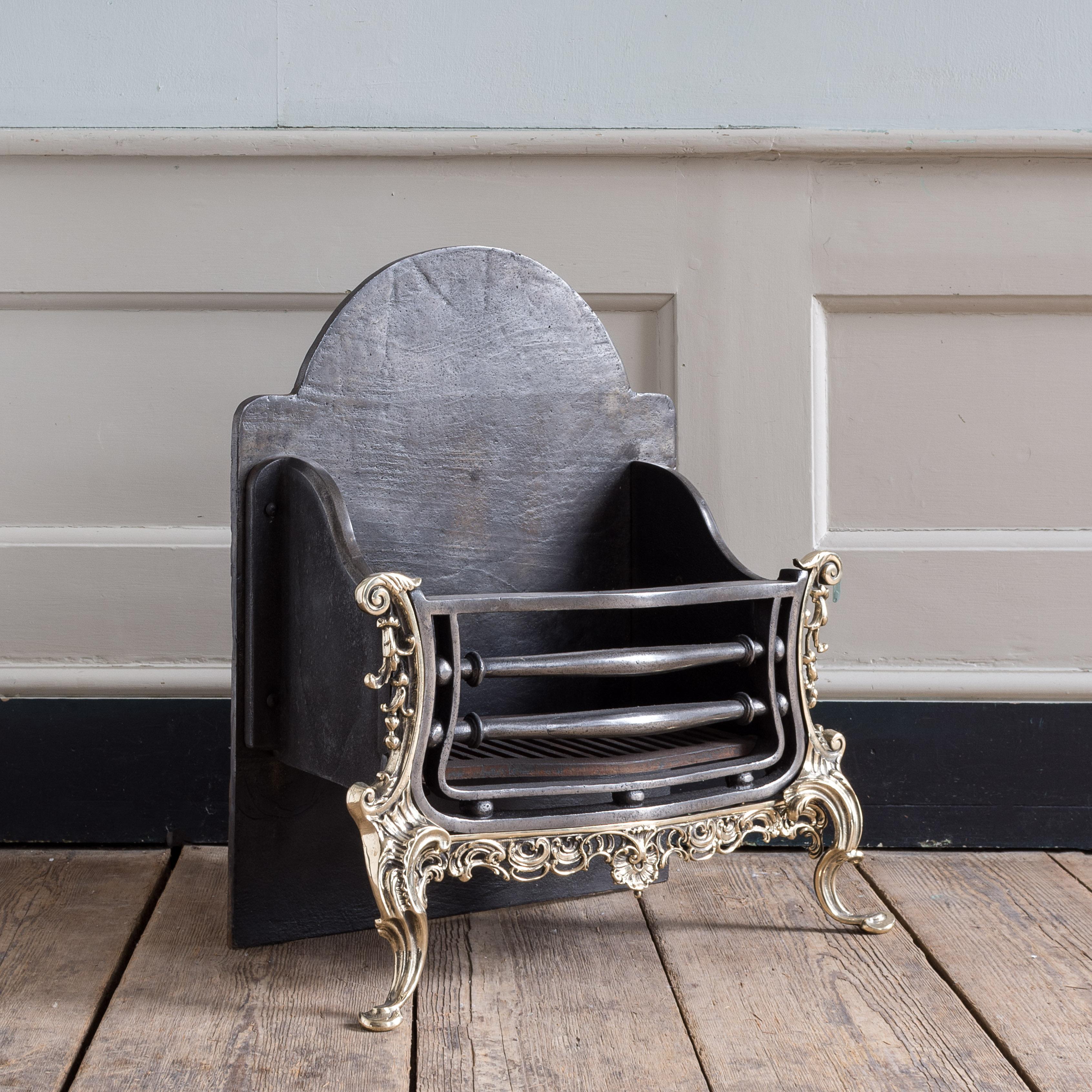 Nineteenth century iron and brass fire grate, with arched back-plate and rococo apron centred by shell motif, on elegant foliate scroll legs.

Restored, re-polished and ready to use immediately.