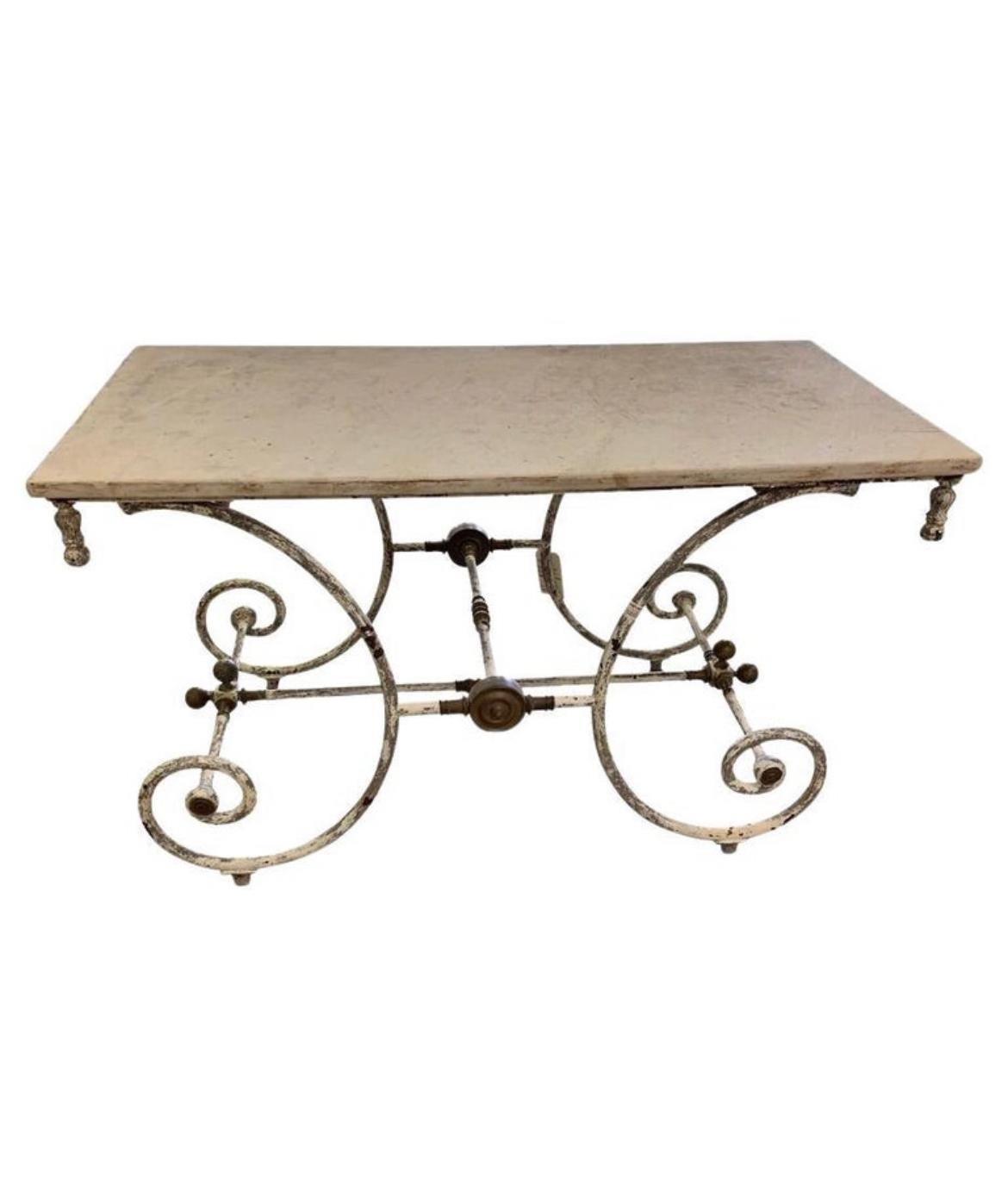 A gorgeous 19th century French marble top pastry table featuring old white painted patina on the iron base. This beauty features decorative brass hardware with patina and a white veined marble top. Ideal for use as a kitchen island or could also