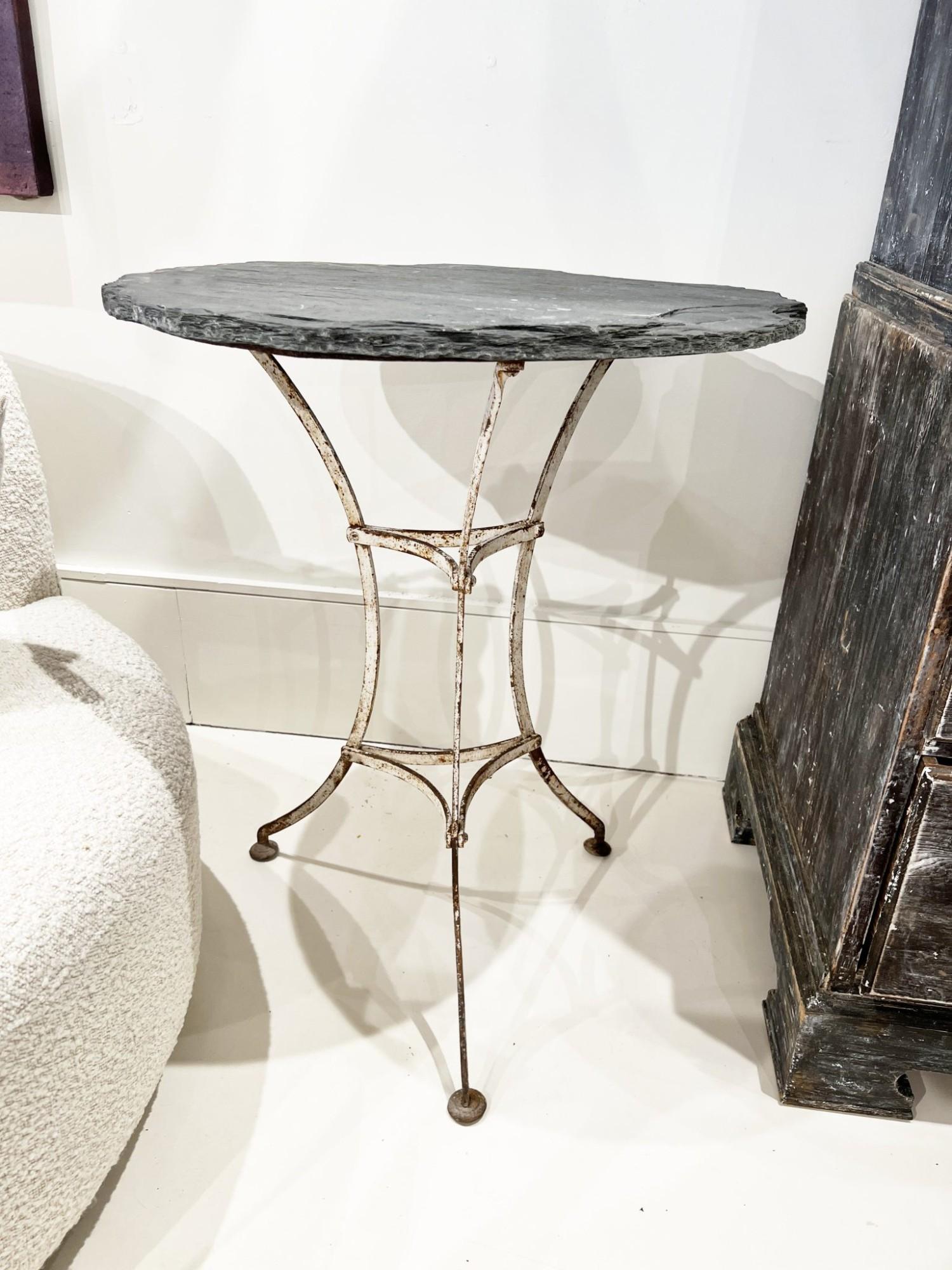 Mesa bistro del siglo XIX con tablero de pizarra - Estilo clásico de cafetería francesa, con base de hierro fundido patinado con intrincados detalles y tablero rústico de pizarra. La rica textura de la pizarra contrasta maravillosamente con las