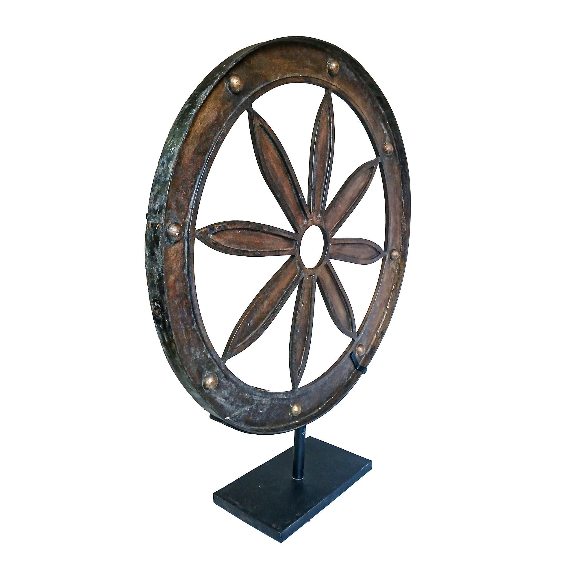 A wrought iron wagon wheel on stand. Indonesia, late 19th Century.

Reclaimed from an old carriage, it has been preserved intact. The inside has been refinished in dark gilt, date unknown. Small metal losses are present due to age and use. 

32