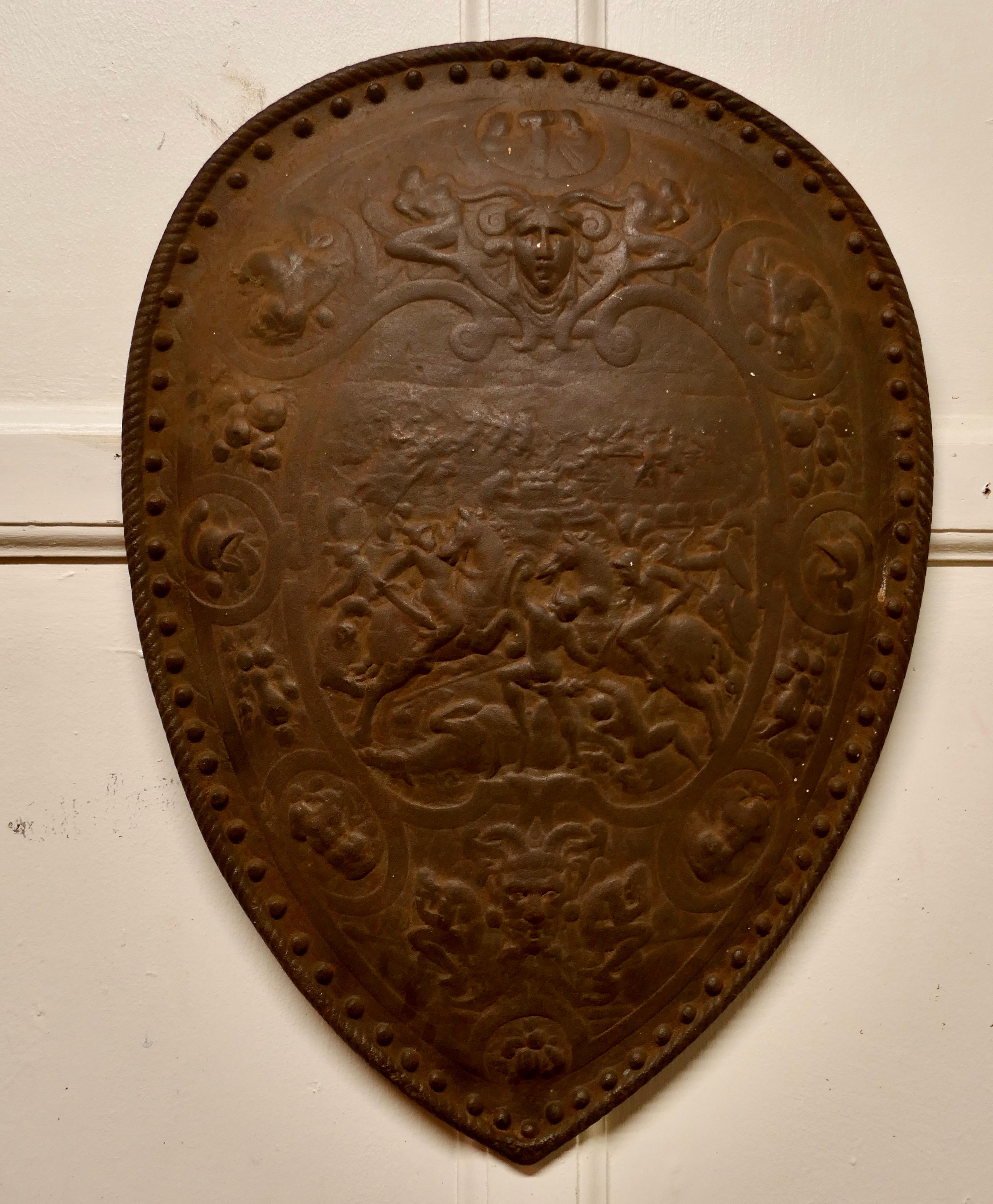 19th century iron wall hanging shield fire back

A Decorative Gothic wall hanging Shield made in solid cast Iron, the shield is decorated with mythical Warriors and beasts, there are 2 images of the green man

The shield is a very heavy