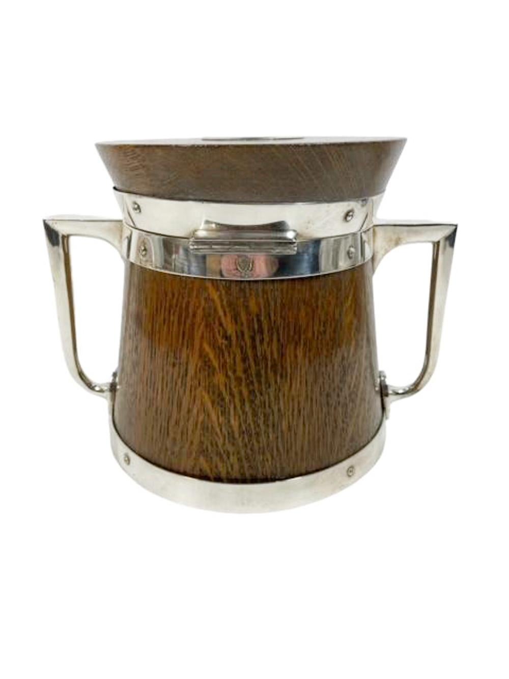 19th Century oak and silver plate ice bucket of staved construction with silver plate bands, handles and shield, having a hinged lid enclosing an ironstone lined interior. Makers mark of John Grinsell & Sons.