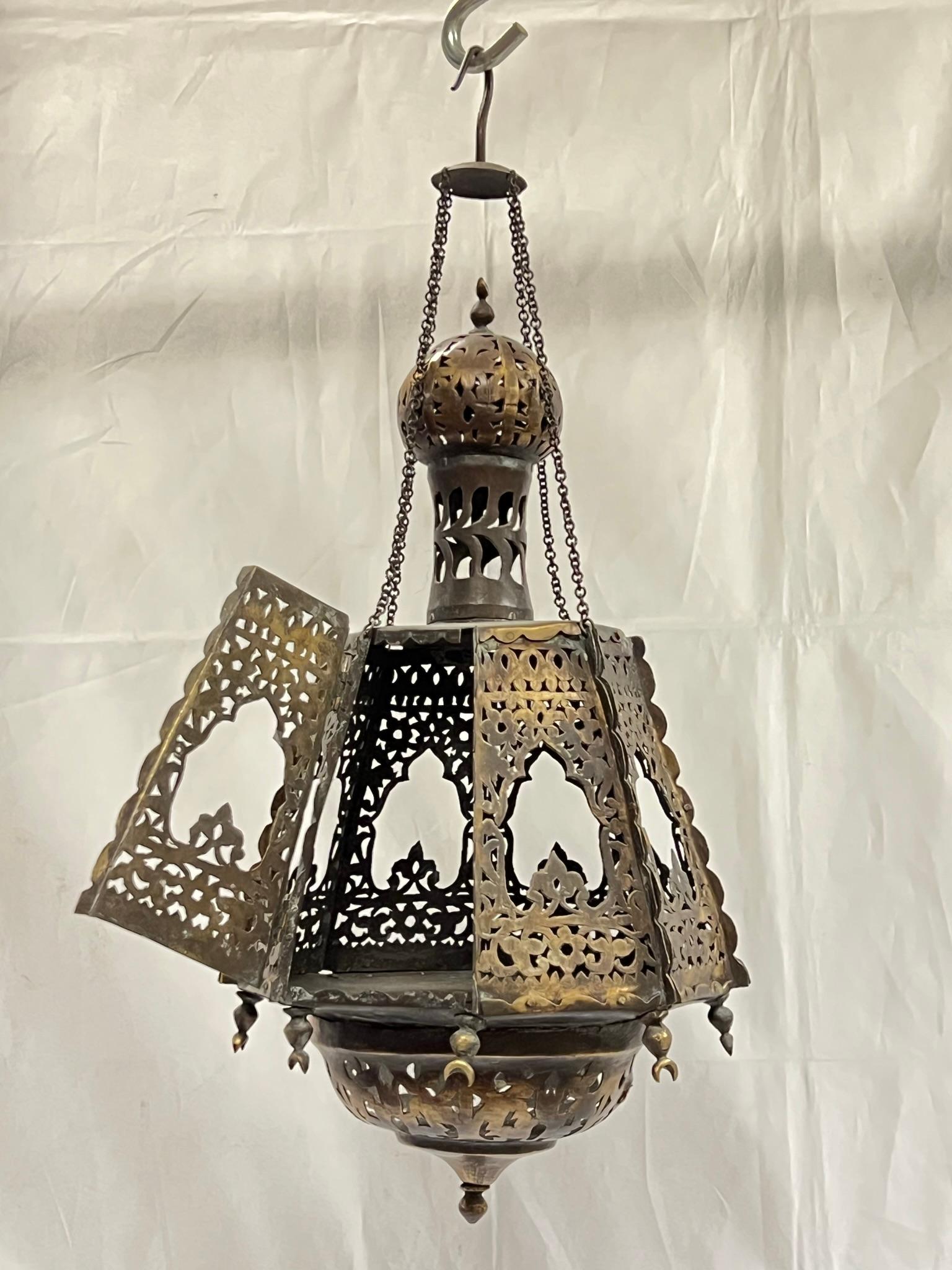 Antique openwork metal lantern with minaret top, Islamic crescent moon designs, and hexagonal shaped body with door on hinge revealing open compartment to house candles.