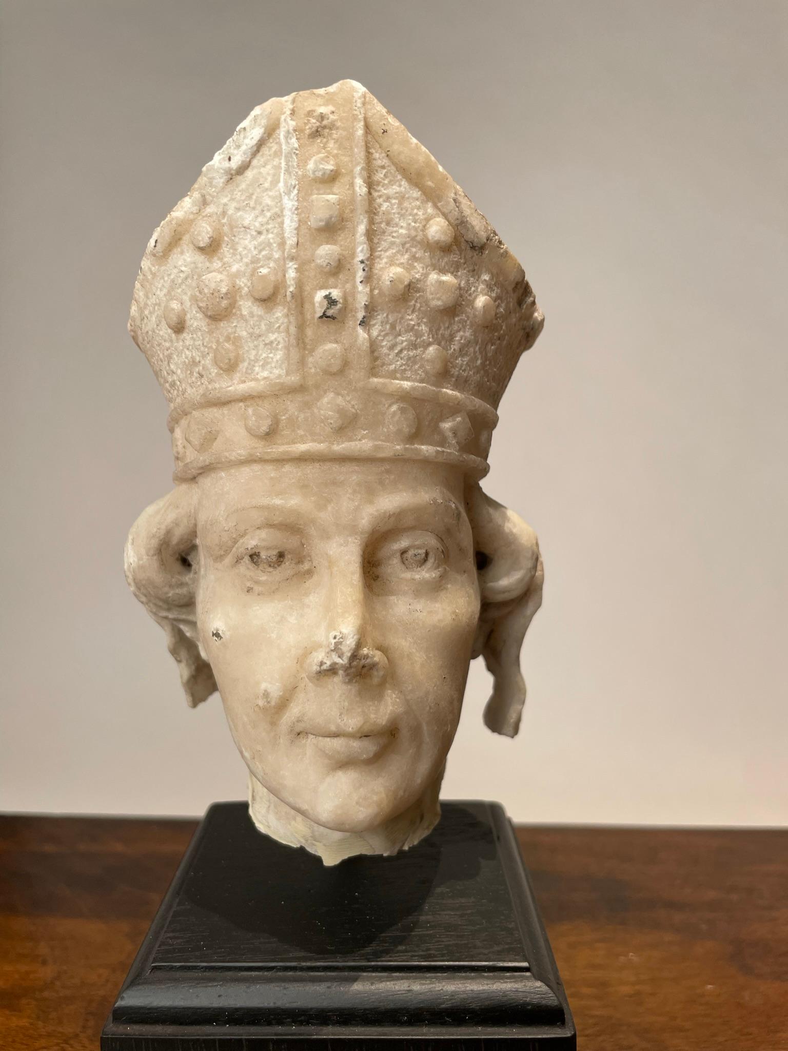 Italienischer geschnitzter Alabasterkopf eines Heiligen mit Bischofsmitra im gotischen Stil aus dem 19. Obwohl es sich um ein Fragment handelt, verleiht der intensive Blick dieser kleinen Schnitzerei ihr eine große Präsenz. Dieses von einem