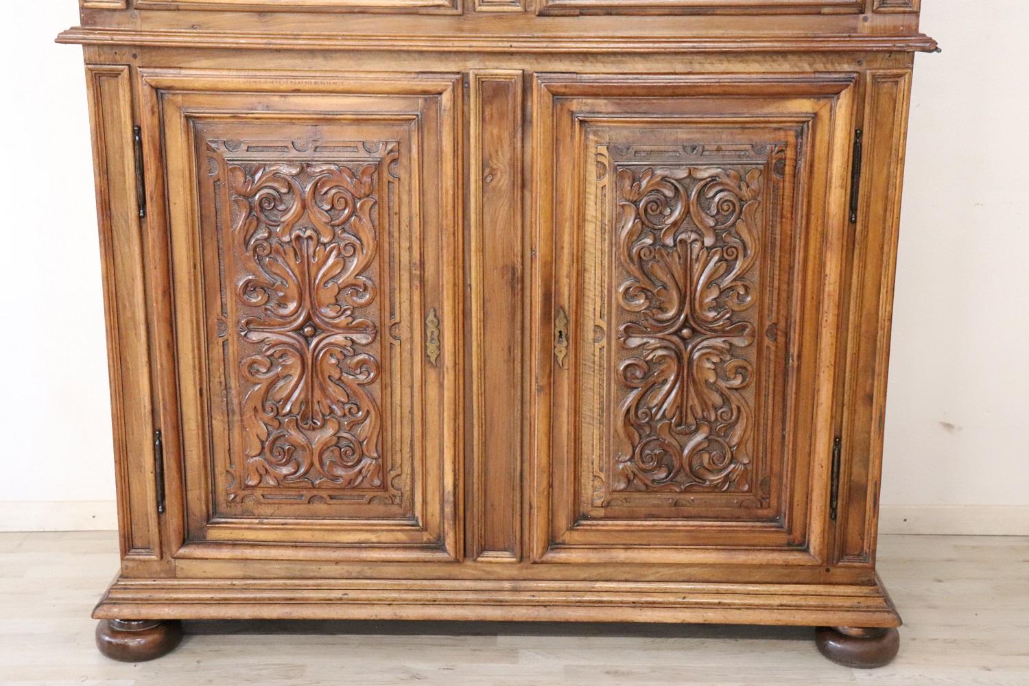 Important and rare antique solid walnut cabinet, 19th century. Characterized by a refined hand carving of the wood on the front doors. The fine walnut wood has acquired a beautiful old patina. Internally large useful space, equipped with shelves