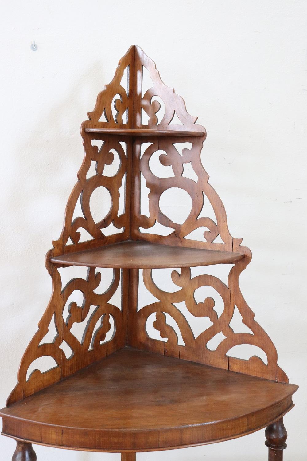 19th century Italian antique corner shelves. High quality furniture in solid walnut wood. Characterized by a refined openwork decoration at the top with curls and scrolls. On the sides, two elegant turned columns smile the tops. Equipped with three
