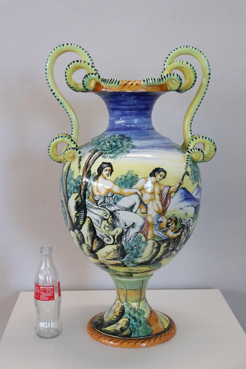 Large Italian-made majolica vase in the shape of an amphora. Refined hand-painted decoration of classic taste with characters and landscapes. Two large snake-shaped handles. Present brand at the base.