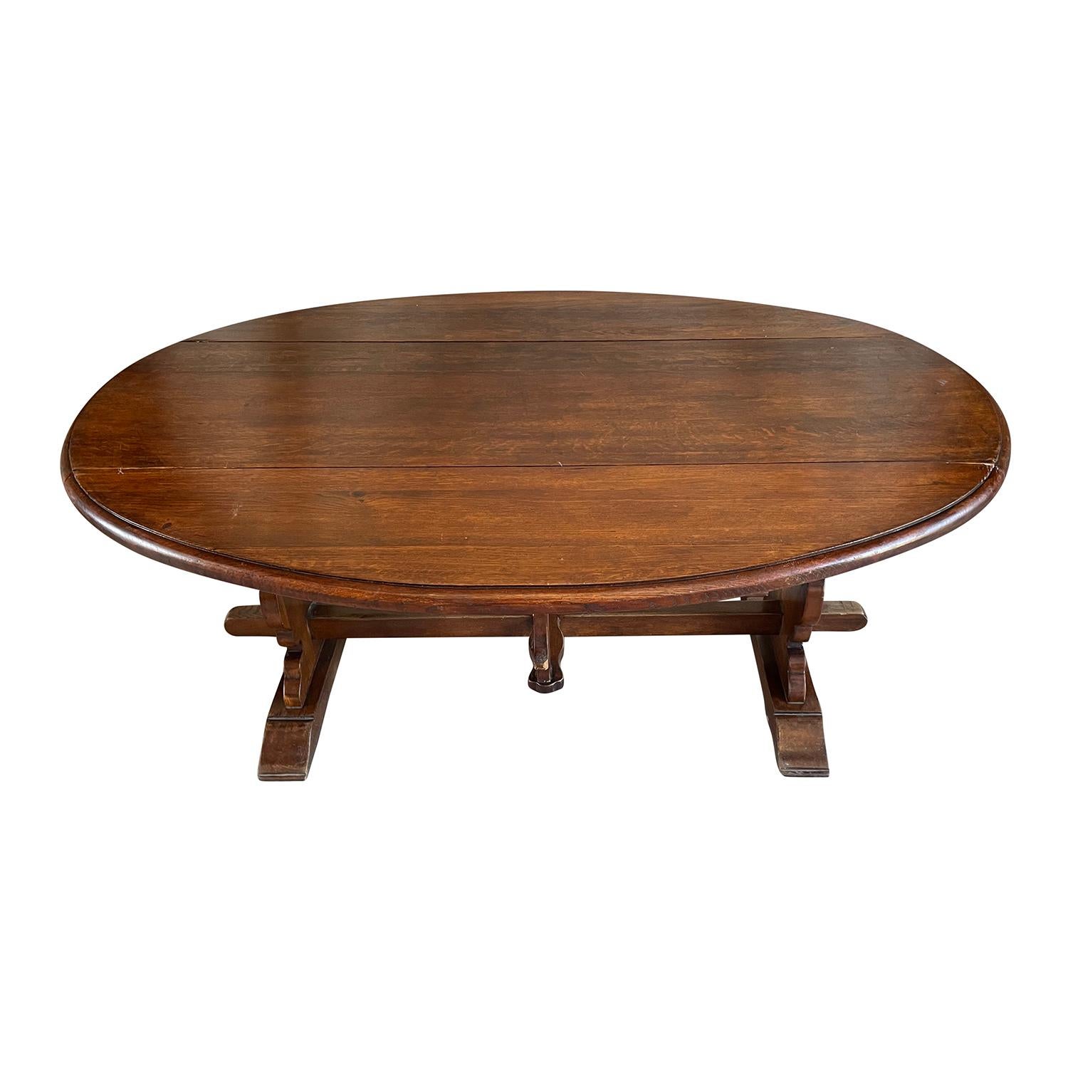 An antique Italian small oval dining table with foldable sides. This Tuscan table is made of hand crafted Walnut and supported by a substantial trestle design base, in good condition. Hand waxed finish, wear consistent with age and use. Circa 1900,