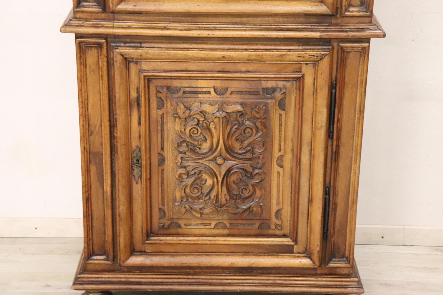Important and rare antique solid walnut small cabinet, 19th Century. Characterized by a refined hand carving of the wood on the front doors. The Fine walnut wood has acquired a beautiful old patina. This cabinet splits into two parts for convenient