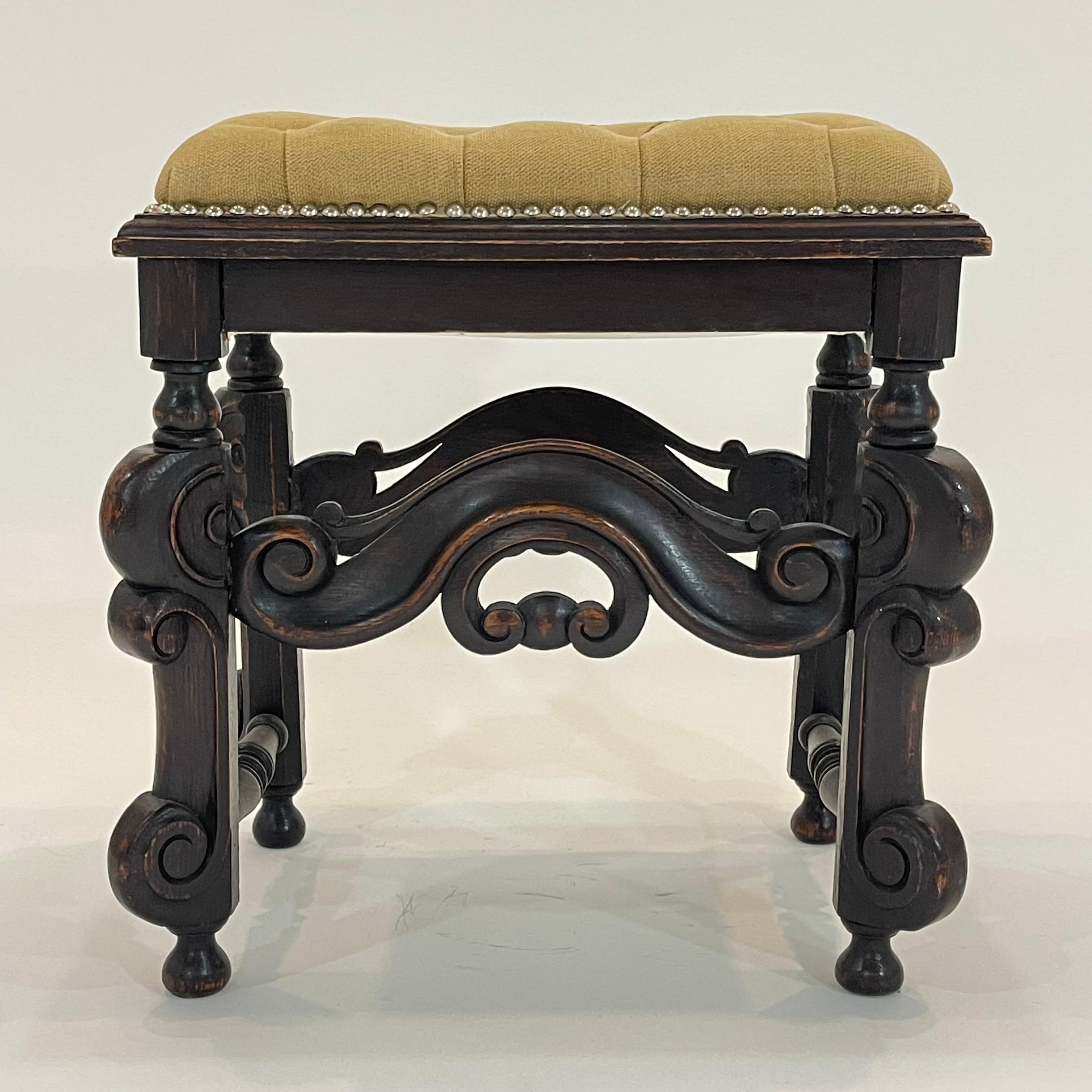 Beautiful antique Baroque stool or bench, rendered in a hand carved oak frame with stunning scroll detail and upholstered in a natural linen button tufted seat cushion with leather piping and nailhead trim, Italy, 19th century.