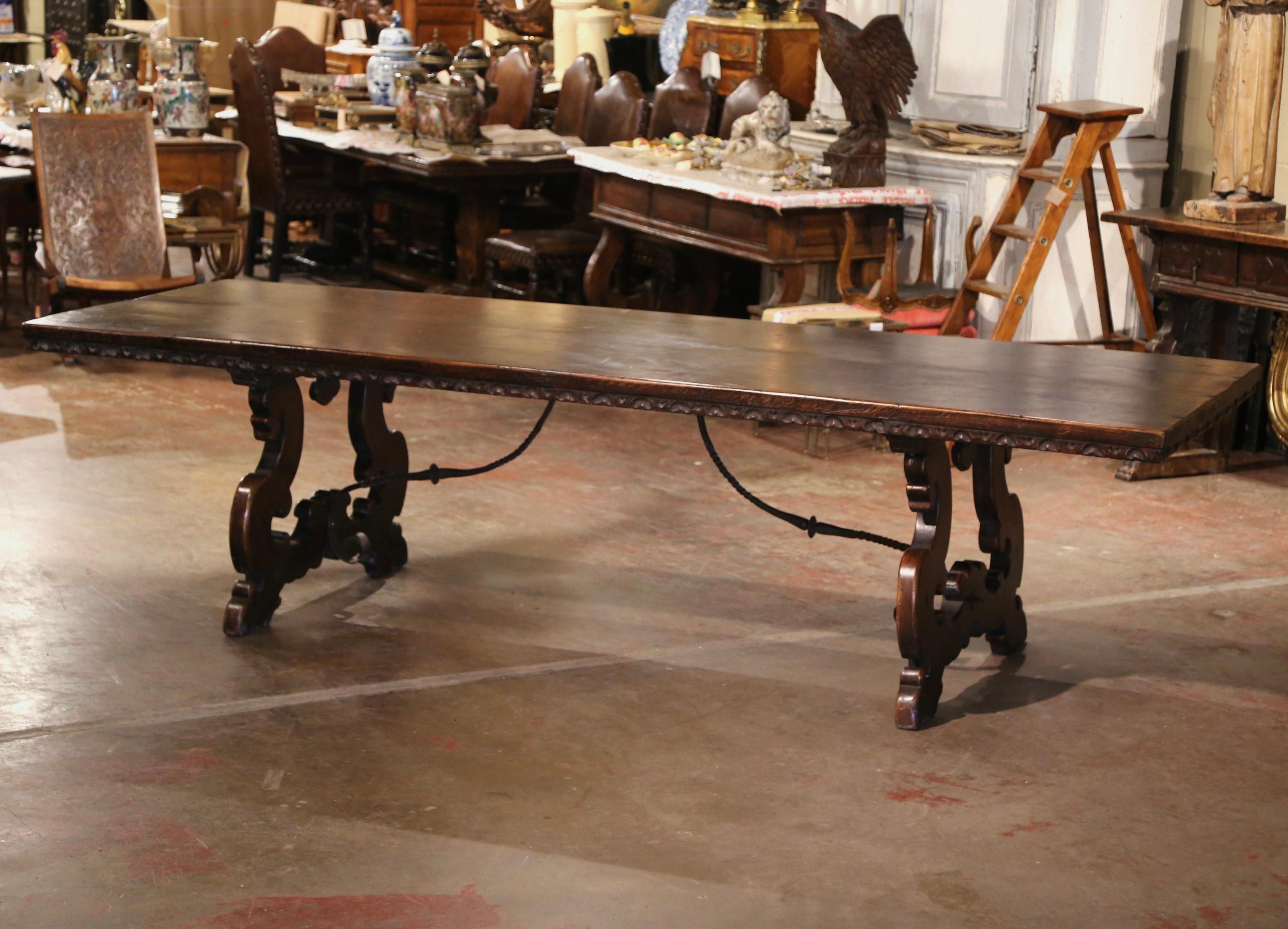 Entertain in style with this monumental 10 feet antique dining room table! Crafted in southwest Italy, circa 1860, and built of solid walnut, the large trestle table stands on hand carved scroll supports ending with paw feet, and joined at the legs