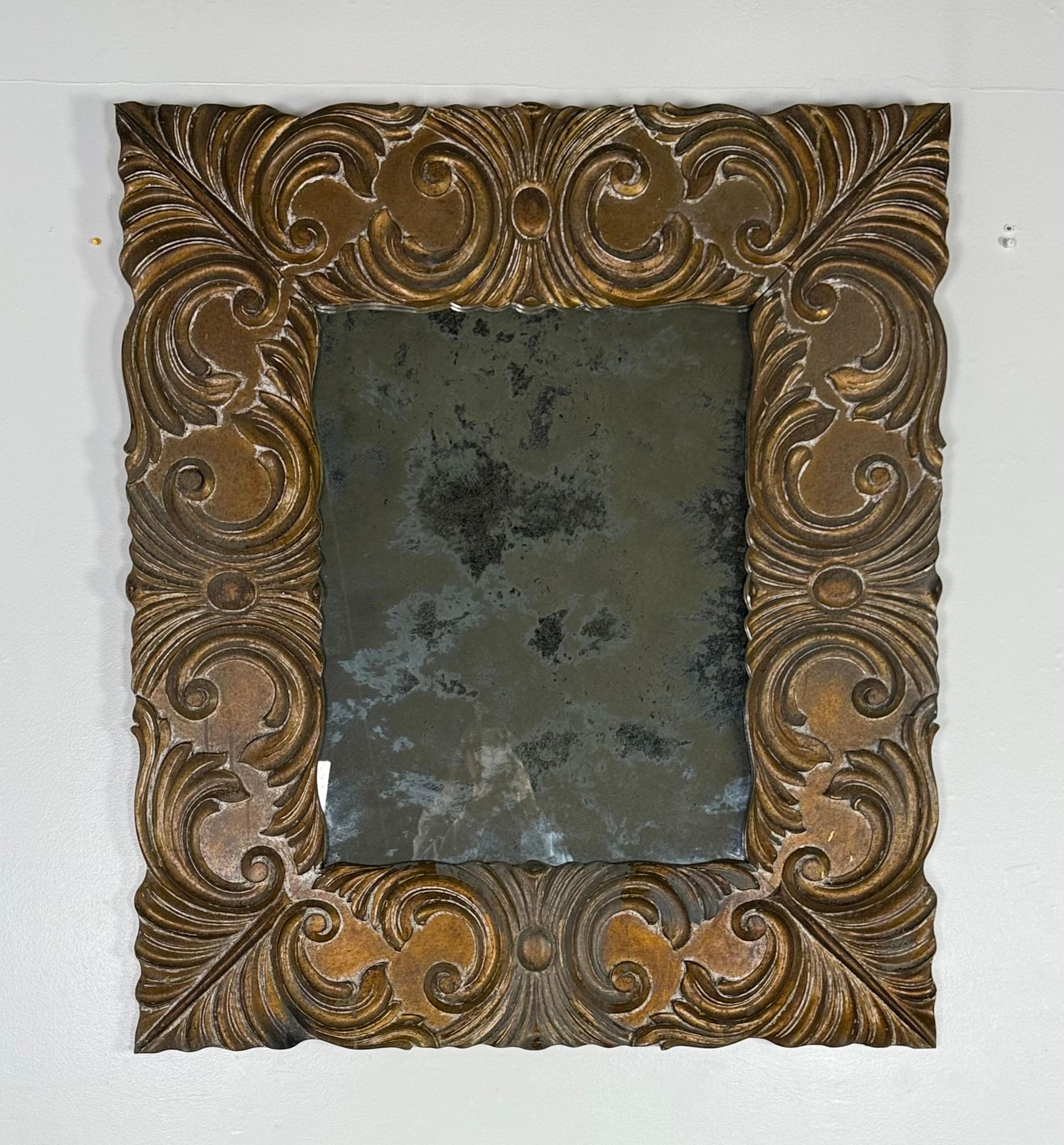 An Italian Baroque mirror dating to the early 19th century, featuring a richly carved wooden frame with deep scrolling acanthus and foliate motifs. The bold, sculptural carving gives the piece strong architectural presence and visual movement.

The