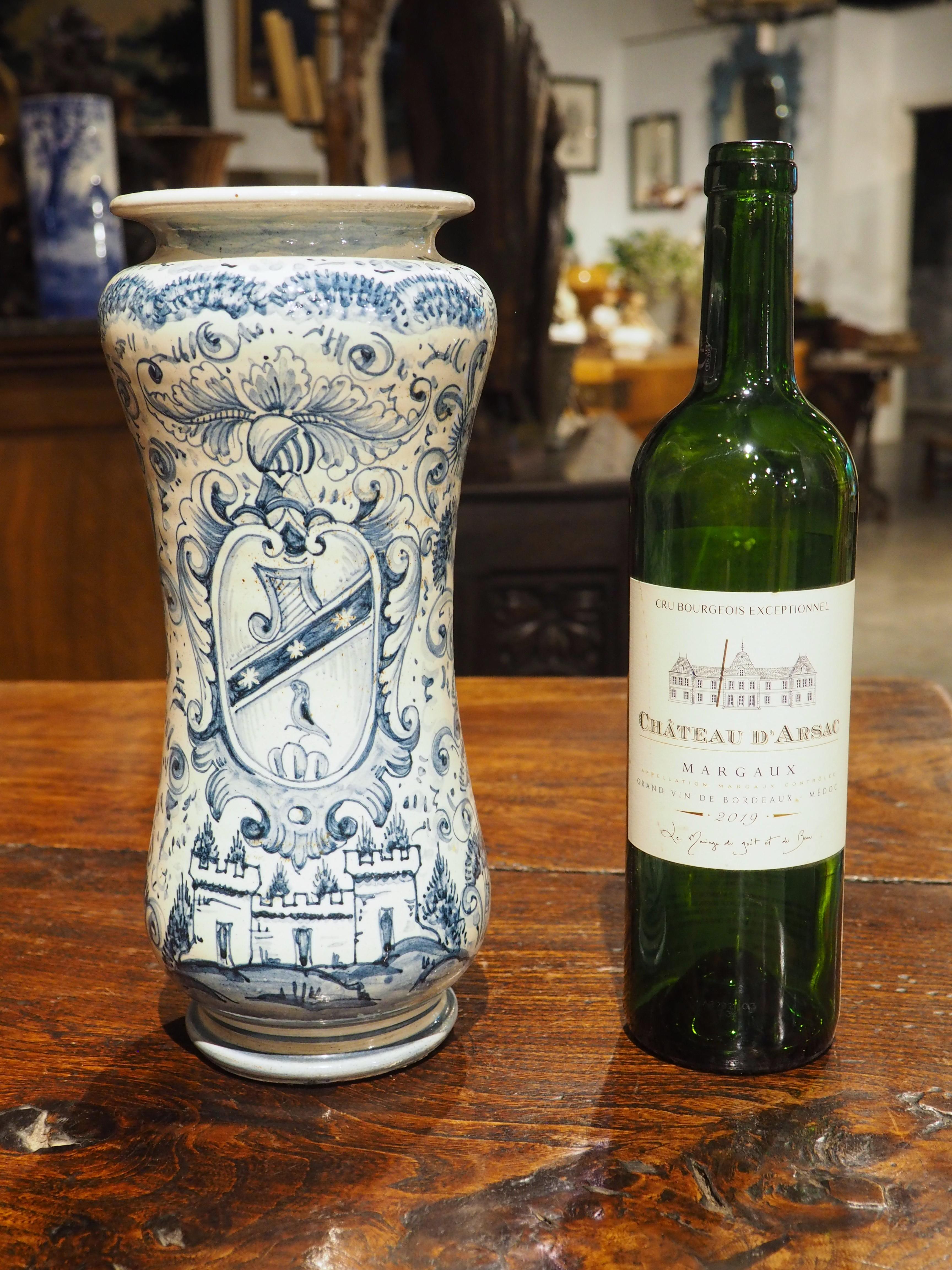 Ricorda la combinazione di colori dei Delftware, questo vaso Albarello con armoriale blu e bianco risale al 1800. Il fondo bianco sporco del vaso italiano è in evidenza sul verso, mentre il fronte è ornato da un grande cartiglio con stemma sopra un