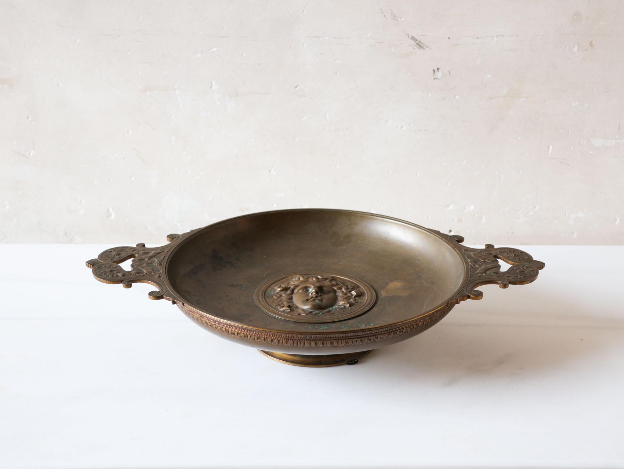 Italian bronze Grand Tour Tazza dish with Medusa. This Tazza or Compote from the 19th century is made entirely of bronze and is characterized by elegant handles and a central cartouche in the shape of Medusa, whose mouth is slightly opened and
