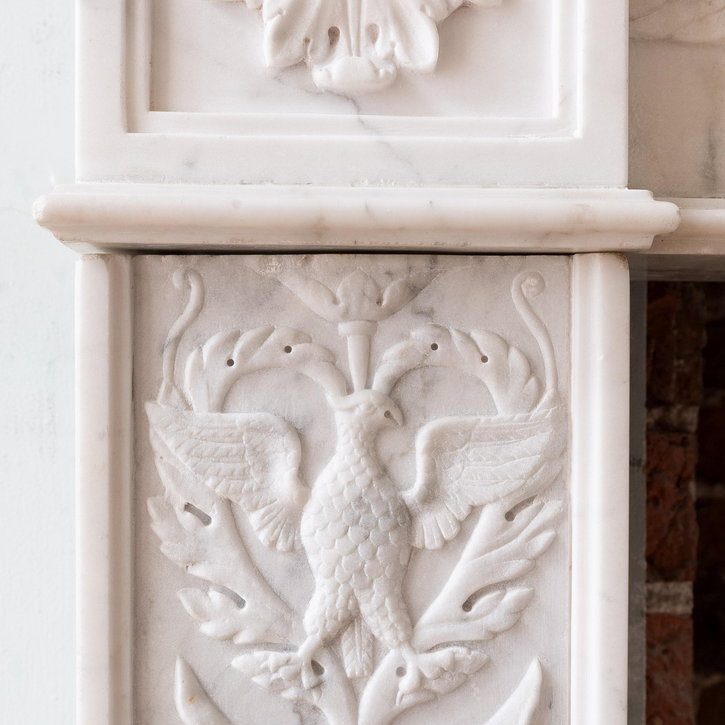 Cheminée en marbre de Carrare et Statuarietto de style Renaissance italienne du XIXe siècle, provenant d'une maison de ville de Belgravia, à Londres.  La frise est sculptée en relief et centrée par une corne d'abondance flanquée d'une lyre, avec des