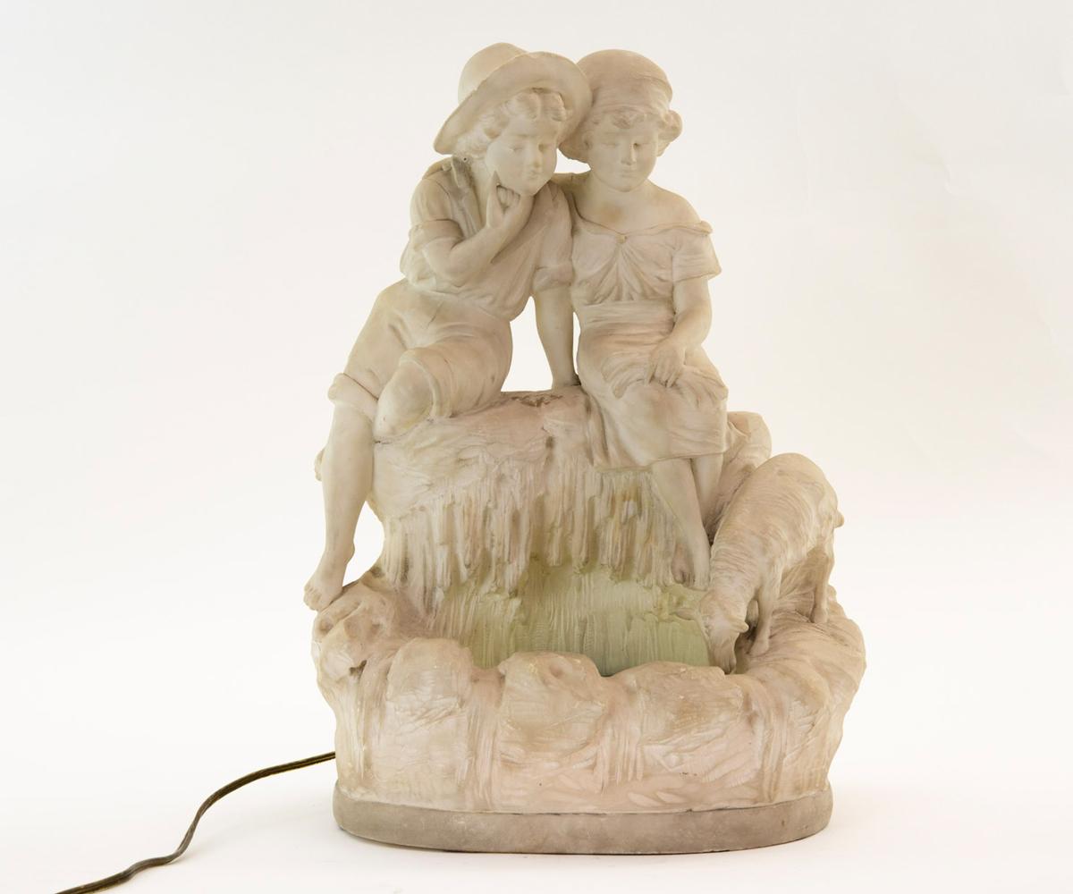 19th century Italian carved alabaster figurine of little boy and girl seating at edge of pond looking at water which is lite up with small light bulbs and blue glass cover over.