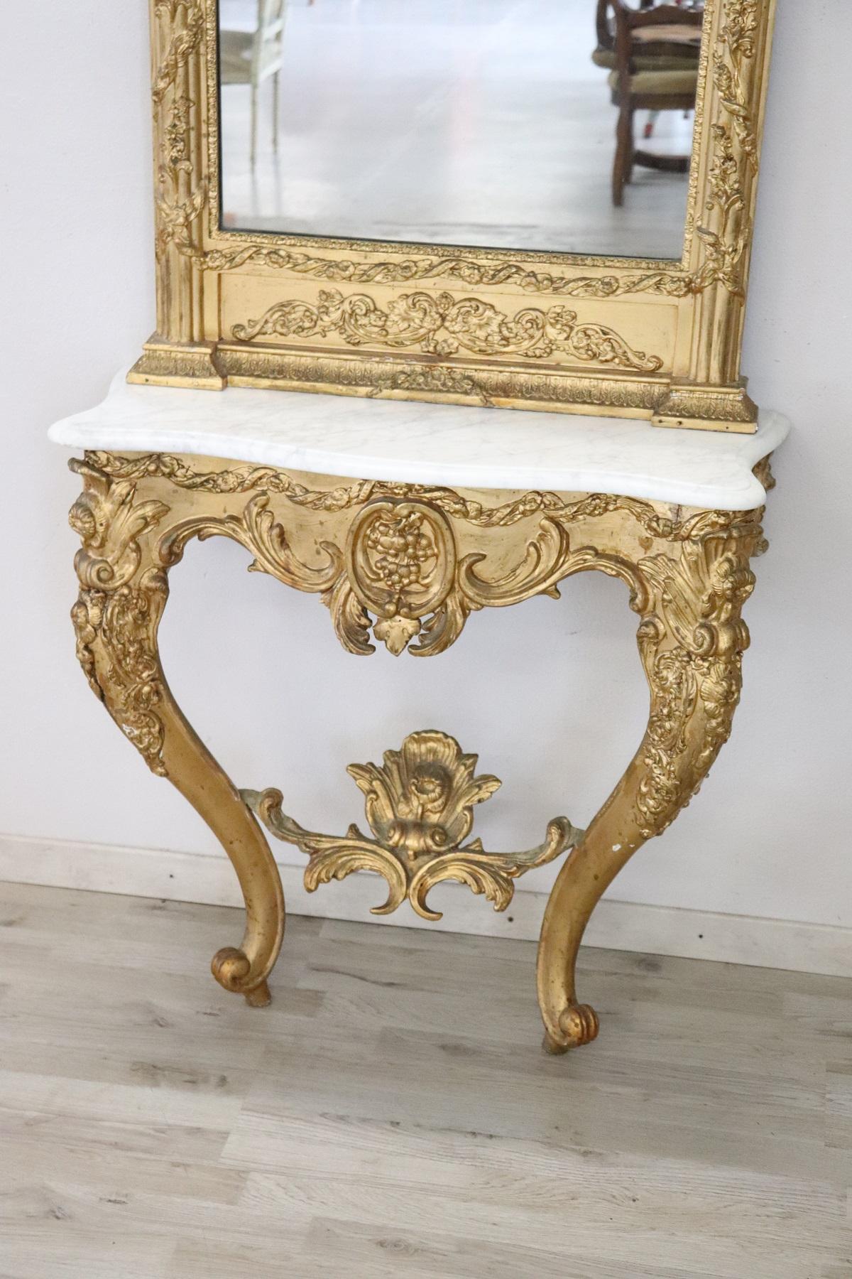 Italian antique console table, 1880. Characterized by precious carved and gilded wood. Each part of the piece of furniture is in larch wood with a fine carving in classic style. The gold plating is in perfect patina gold leaf. The large mirror is