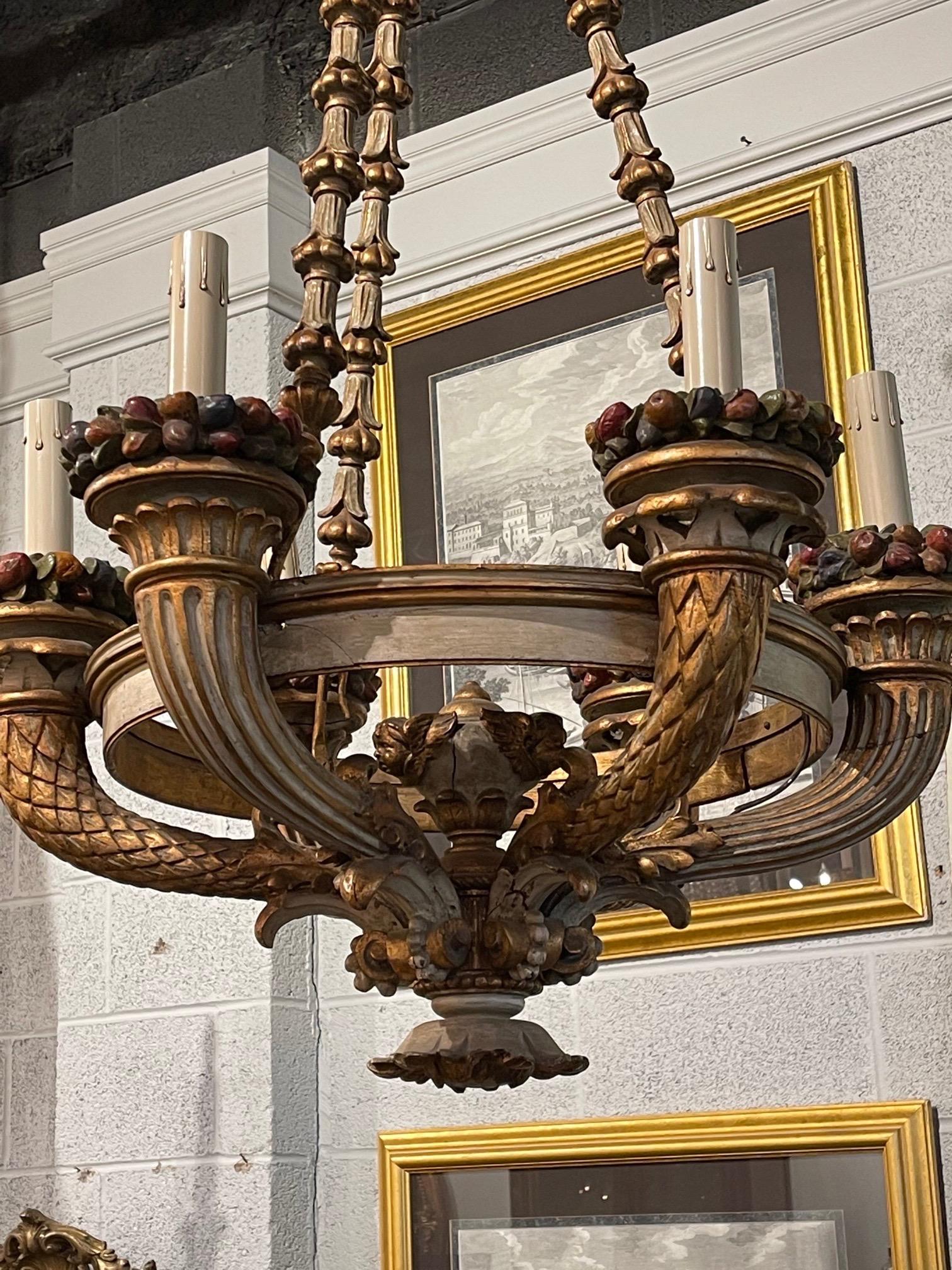 Handsome 19th century Italian carved and painted 6 light chandelier. Exceptional carvings on this piece include an urn with floral images, multicolored berried and an intricately carved wooden chain. Beautiful gilt as well. Amazing craftsmanship!!