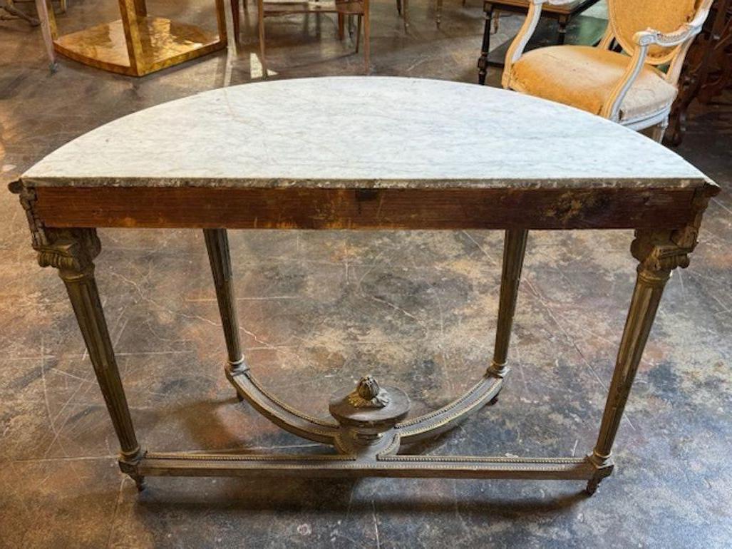 La console Demi Lune neoclassica italiana del XIX secolo, intagliata e dorata, è uno squisito mobile antico caratterizzato da intricati intagli e accenti dorati. Questa console presenta anche un bellissimo piano in marmo.  Con il suo elegante design