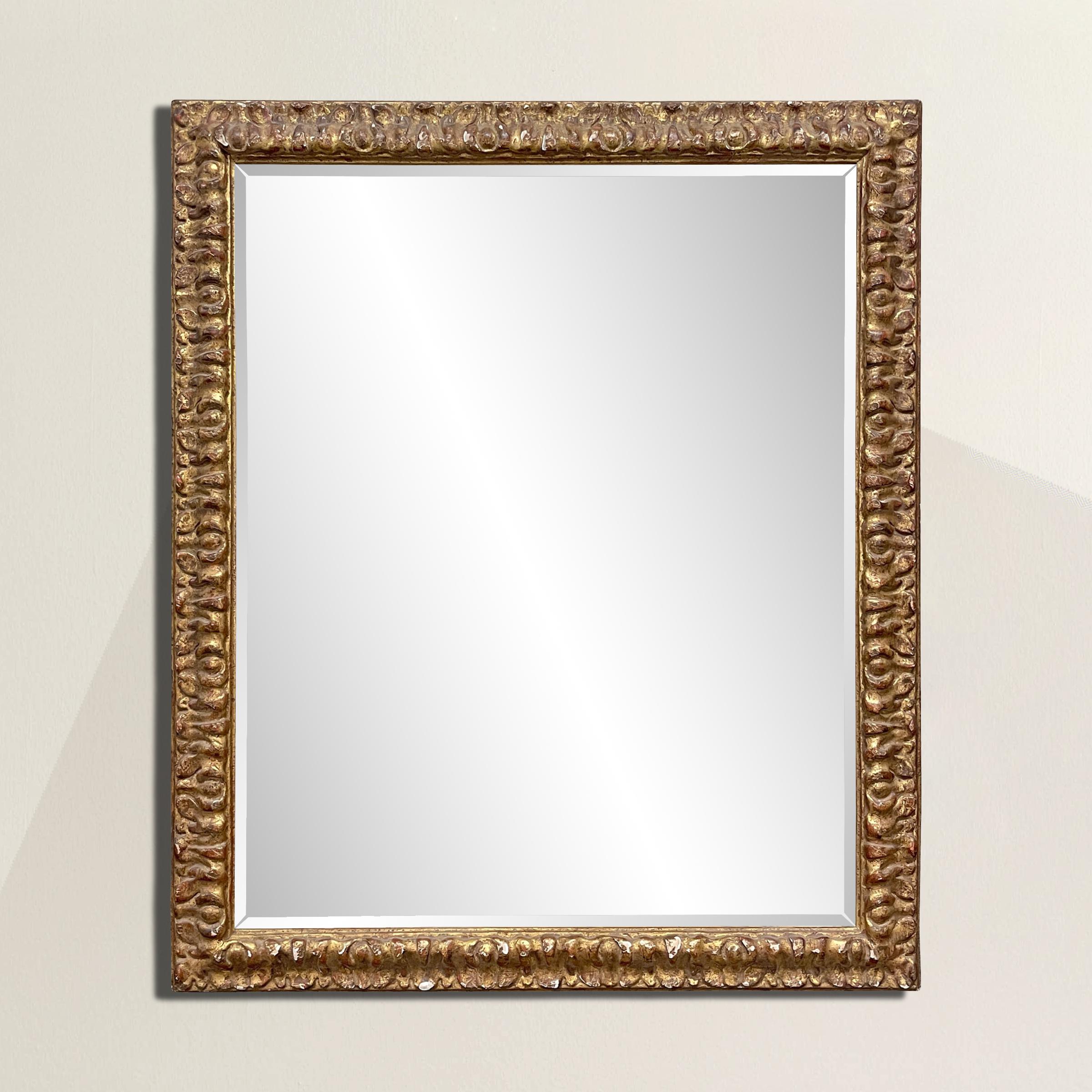 A notable and commanding 19th century Florentine gilt carved wood frame with a stylized floral motif, and a newer beveled mirror. The perfect mirror for over your entry console table, fireplace mantel, or in a bedroom.