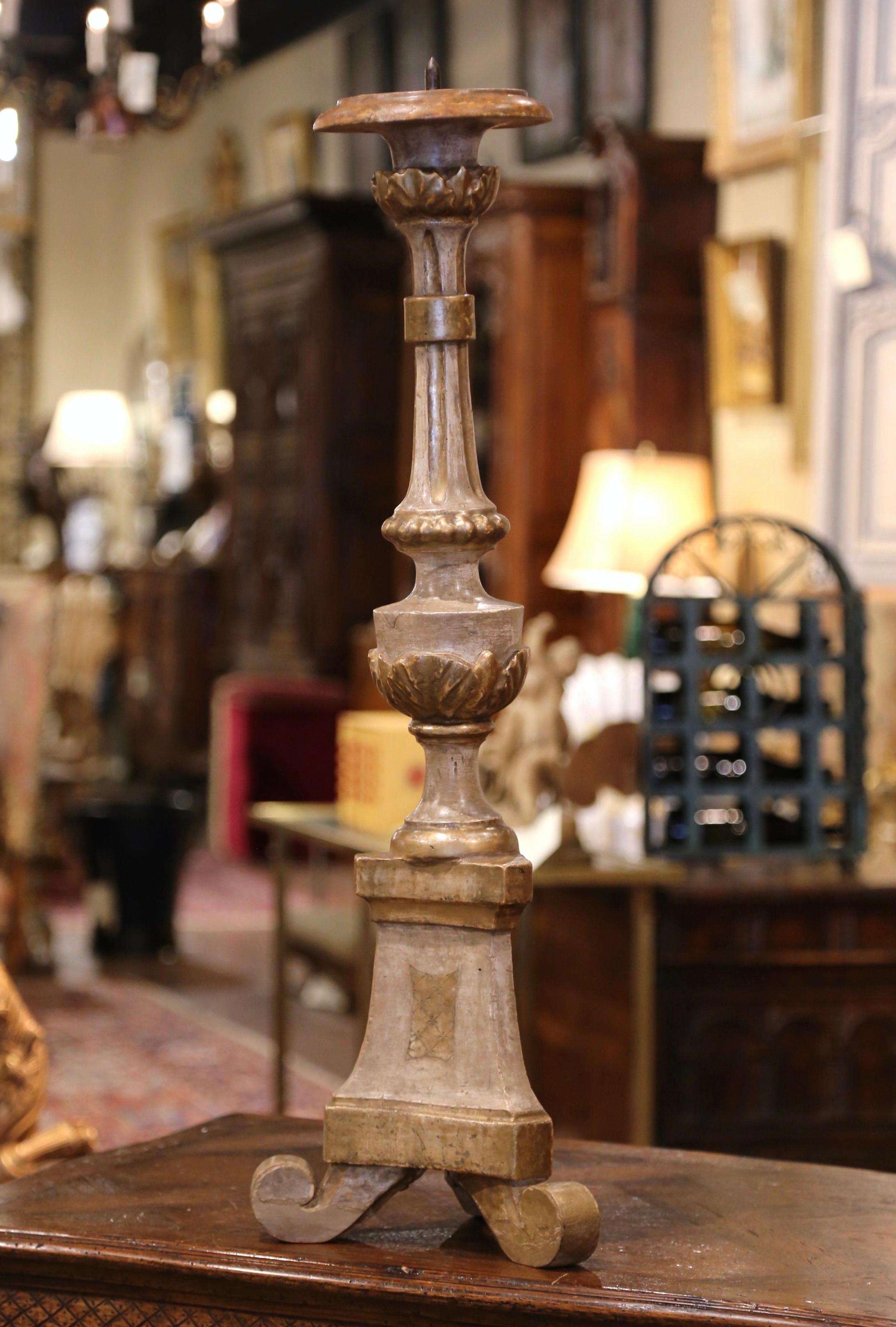 The tall antique candlestick was crafted in Italy, circa 1880. Standing on three scrolled feet over a triangle base, the pic cierge features a carved stem with acanthus leaf motifs and a metal pricket at the top to hold a candle. The candlestick is