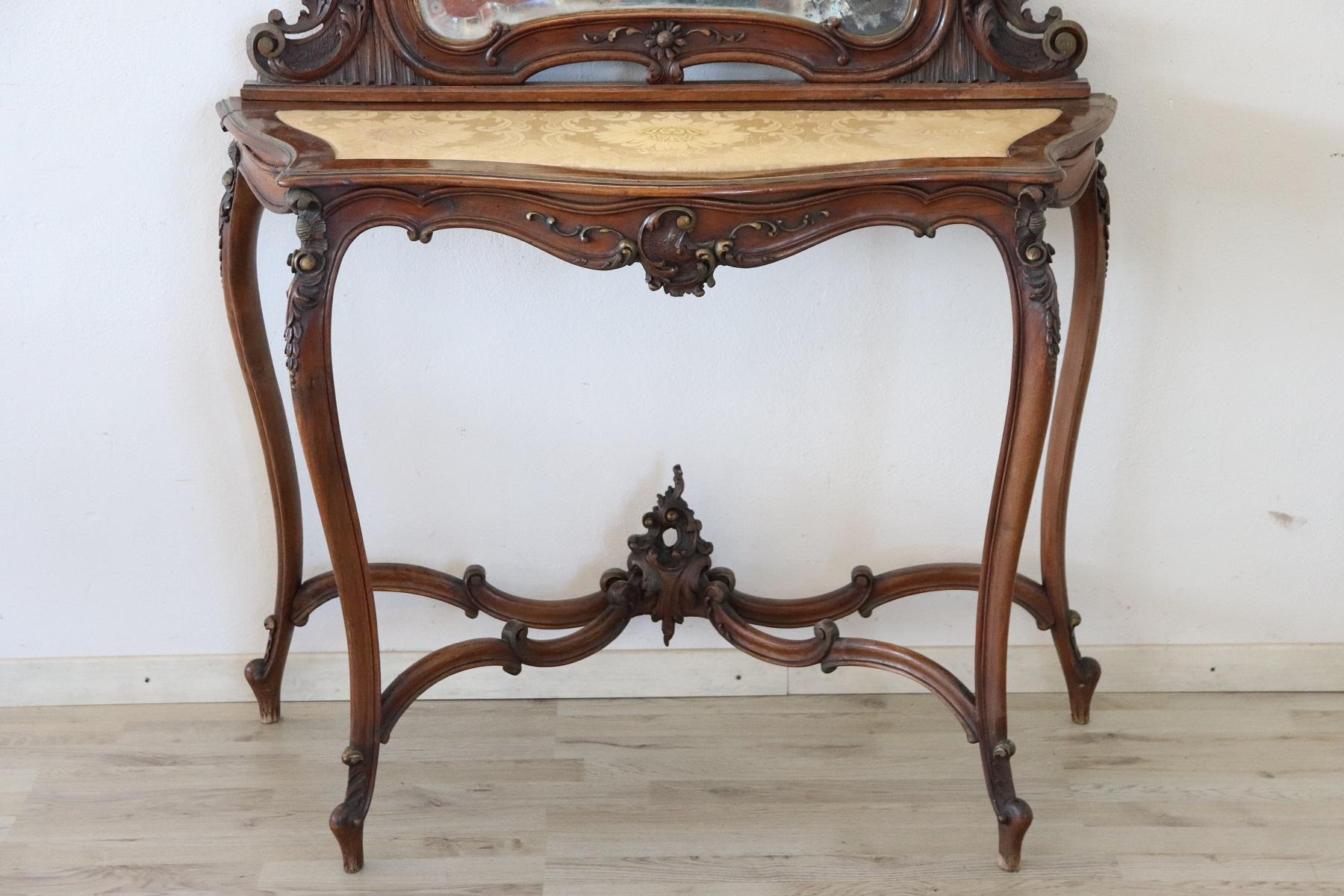 Antique Italian console table 1880s. The console is made of solid carved walnut with many curls and swirls of decoration. Perfect to be placed even in representative entrances. Large antique mirror. The top is covered in refined yellow damask fabric.