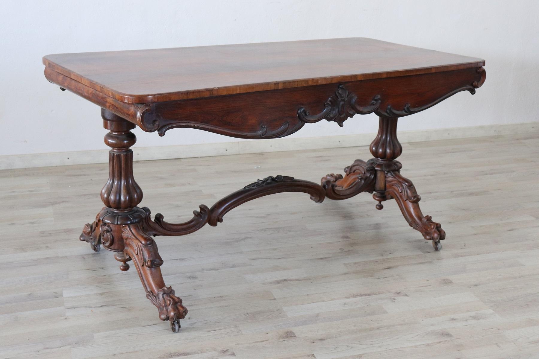 Elegant and antique Italian writing desk, 1880s. The desk is made of solid walnut wood. Important turned and carved legs. Plenty of space for your writing needs. At the feet ancient wheels that allow a comfortable movement.