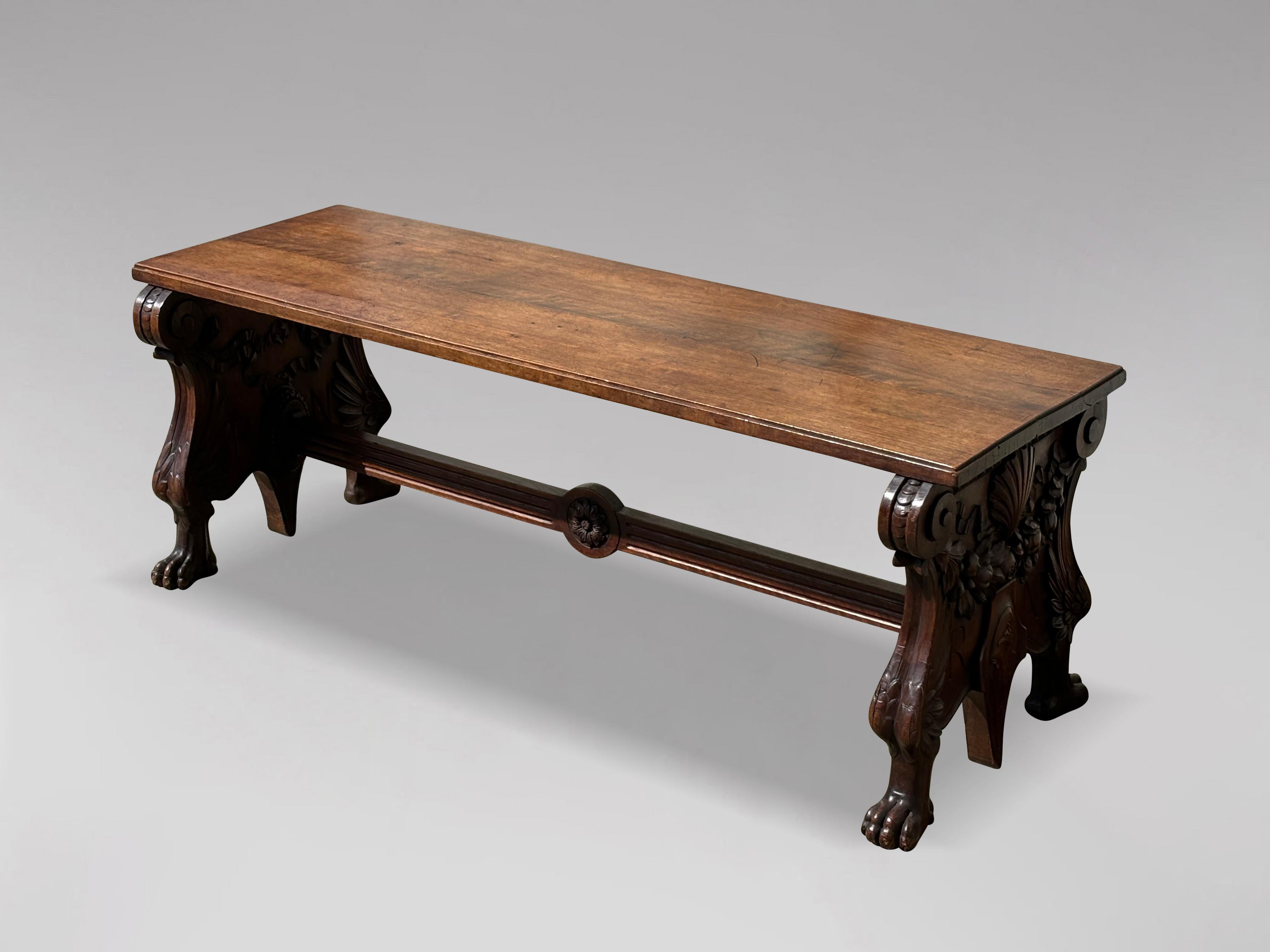Banc ou tabouret en noyer de qualité du XIXe siècle. Un plateau rectangulaire mouluré à deux planches, au-dessus de deux supports d'extrémité sculptés réunis par un châssis cannelé avec des paterae centrales sculptées. Soutenu par des pattes de